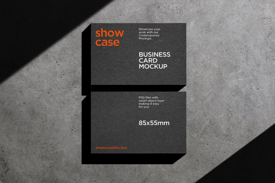 Two black business cards mockup placed on a concrete surface, illuminated by dramatic, angled shadows. The cards feature a modern layout, highlighting their textured, matte finish for a sleek, professional appearance.