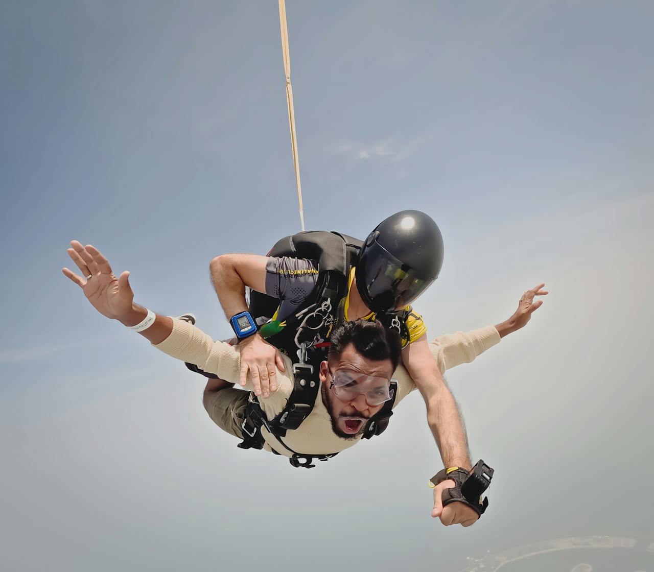 A person is skydiving with a professional wearing a helmet.