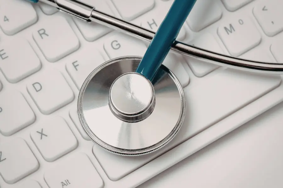 AI nurse communication concept illustrated by a stethoscope resting on a white computer keyboard against a clean, minimal background.