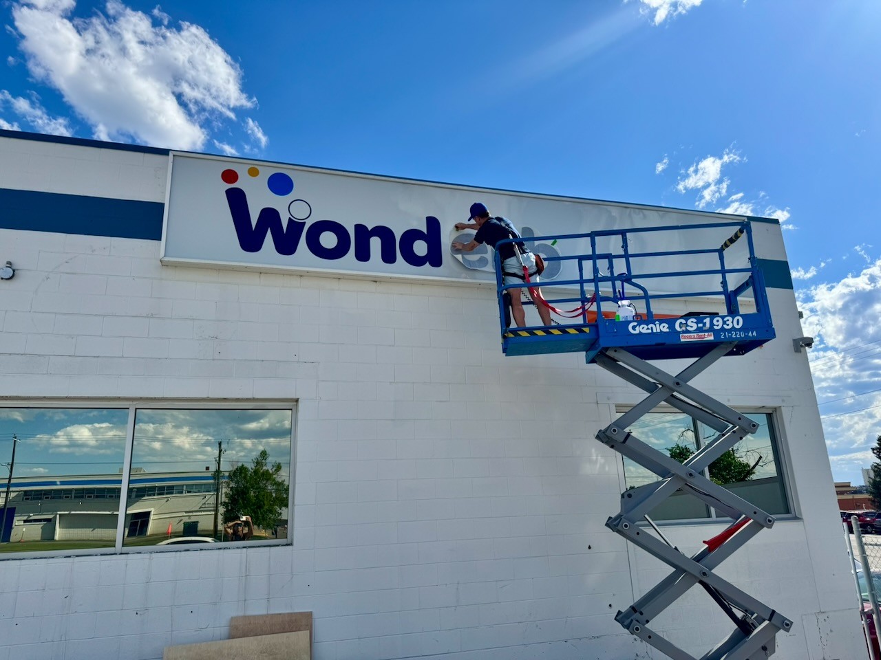 Installing a storefront sign on a commercial building using a scissor lift — DisplayWorks Signs & Graphics in Calgary.