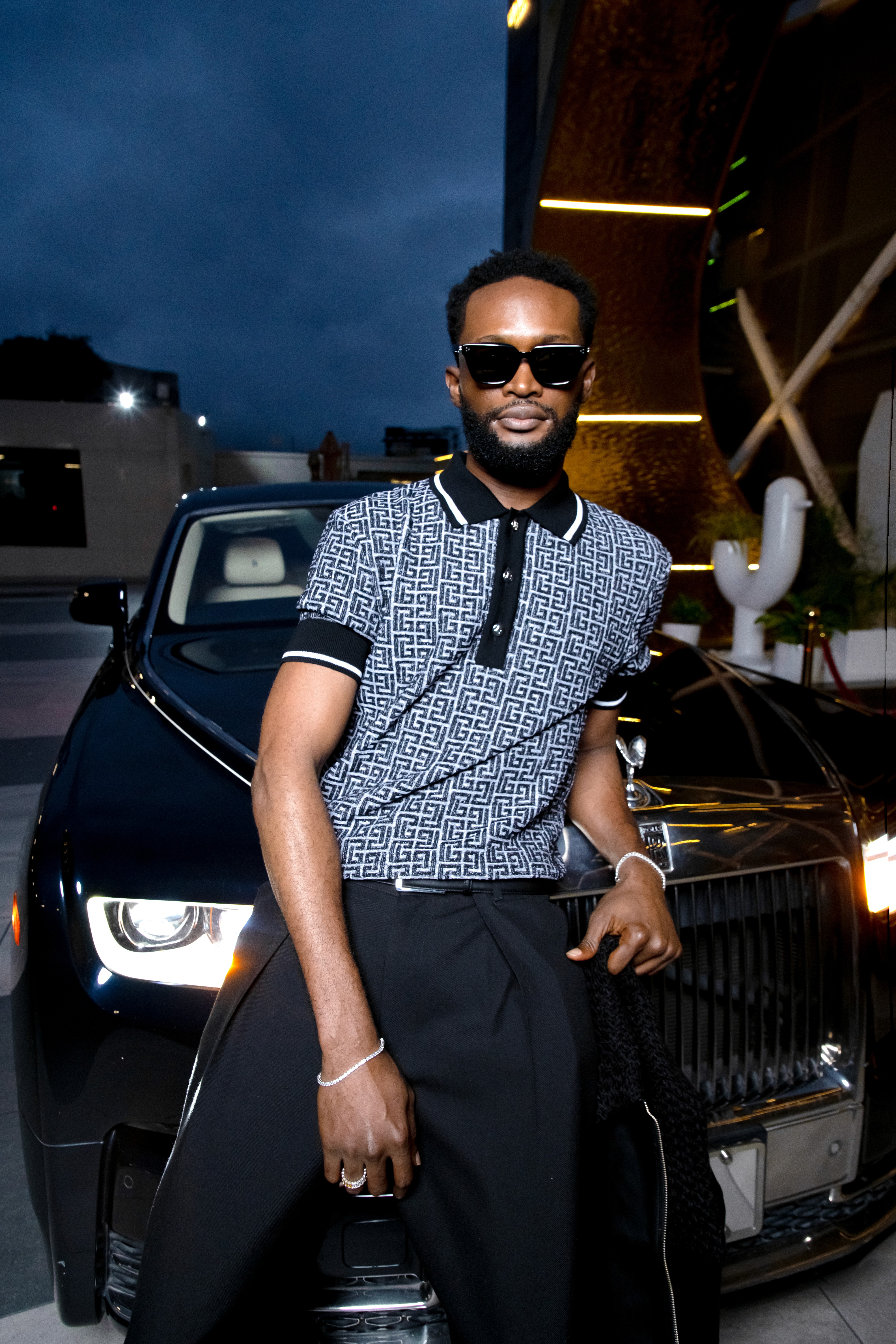 Young man wearing red knitwear and sunglasses on a vibrant green background.