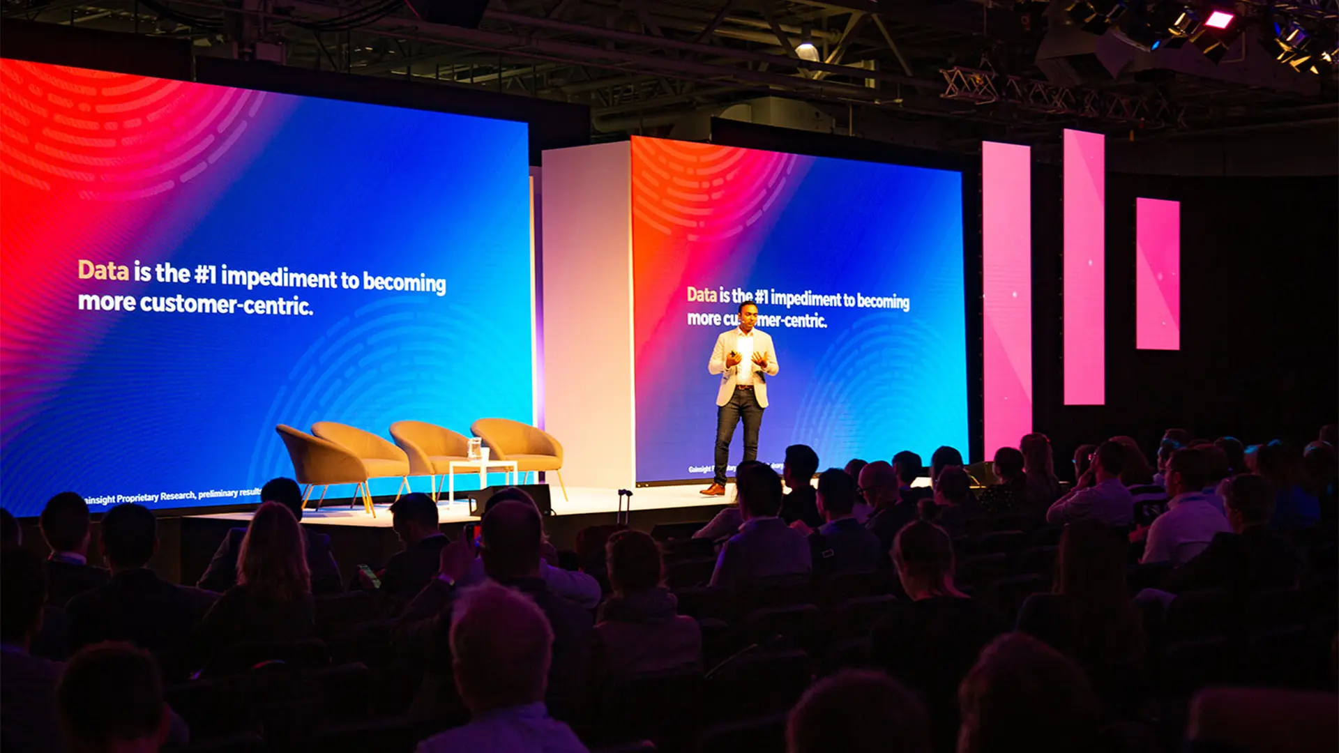 Keynote speaker presenting on a large stage with colourful event screens at Gainsight Pulse.