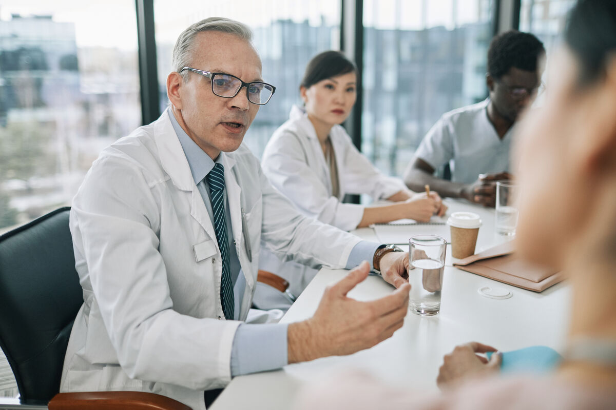 Scientist wearing safety goggles and blue lab attire, using a pipette to transfer liquid into a vial in a laboratory setting.
