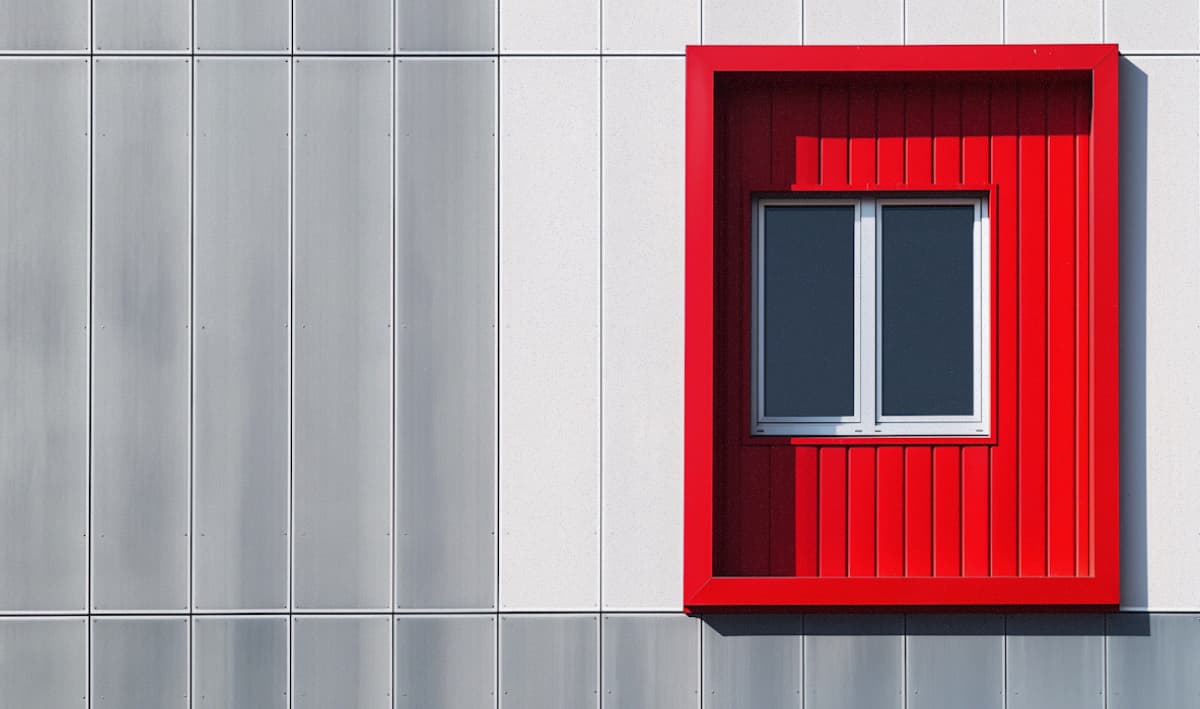 A man sits facing away from us at a desk with multiple monitors
