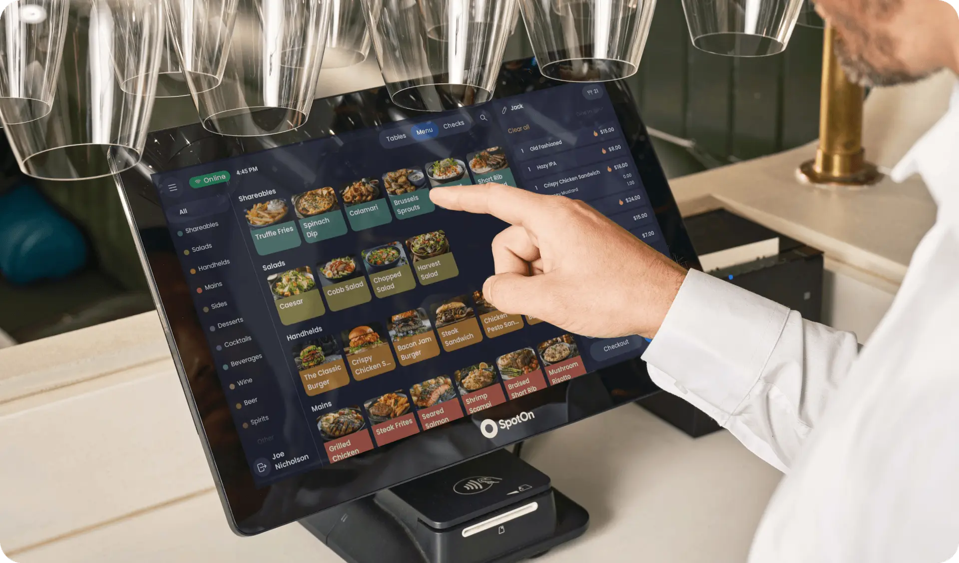 A person interacts with a SpotOn touchscreen point-of-sale system displaying various food options in a restaurant setting in Bradenton, FL.