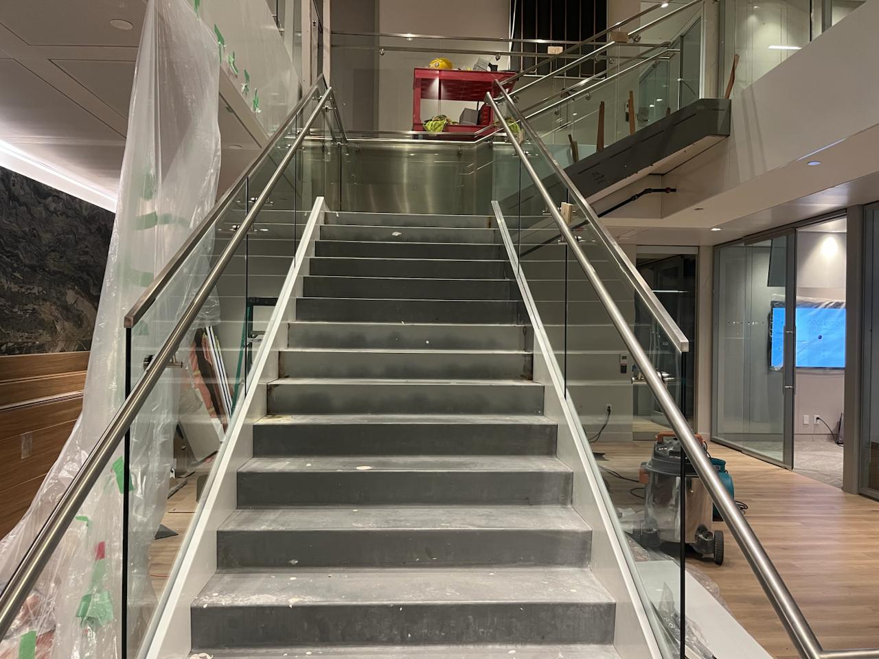 Completed interior steel staircase with glass guards and metal handrails
