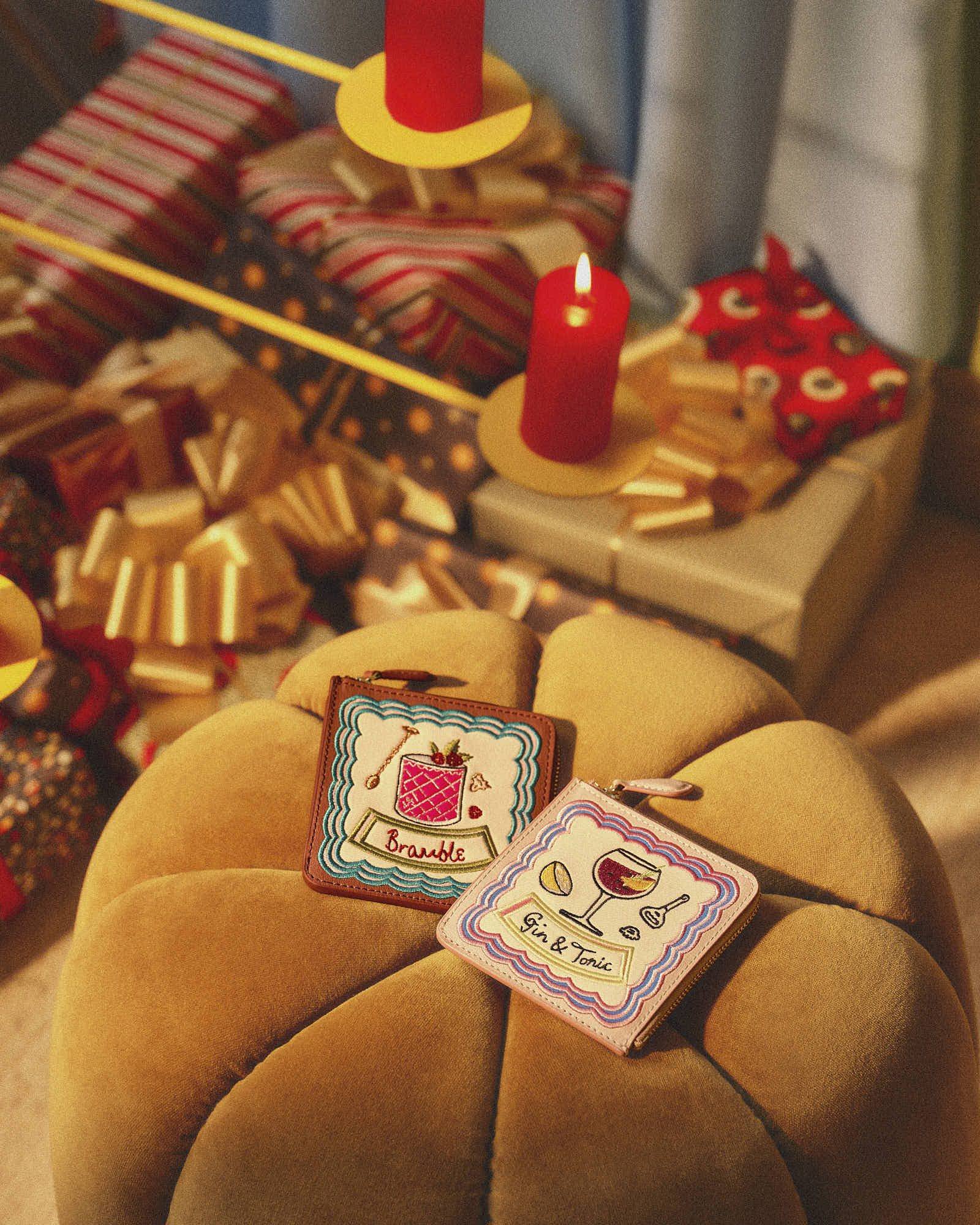 Festive holiday setting with wrapped gifts, lit candles, and embroidered drink coasters.