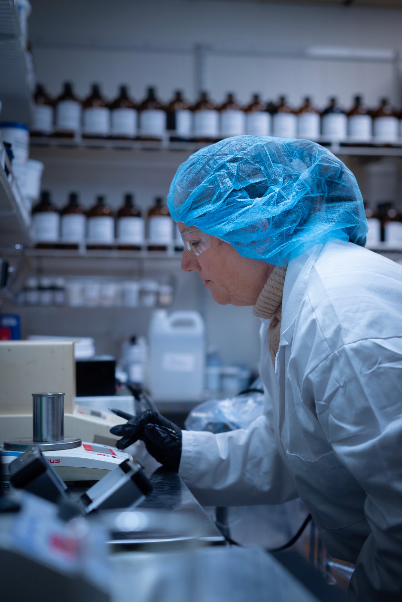 female chemist weighing cup on scale at stellar chemical