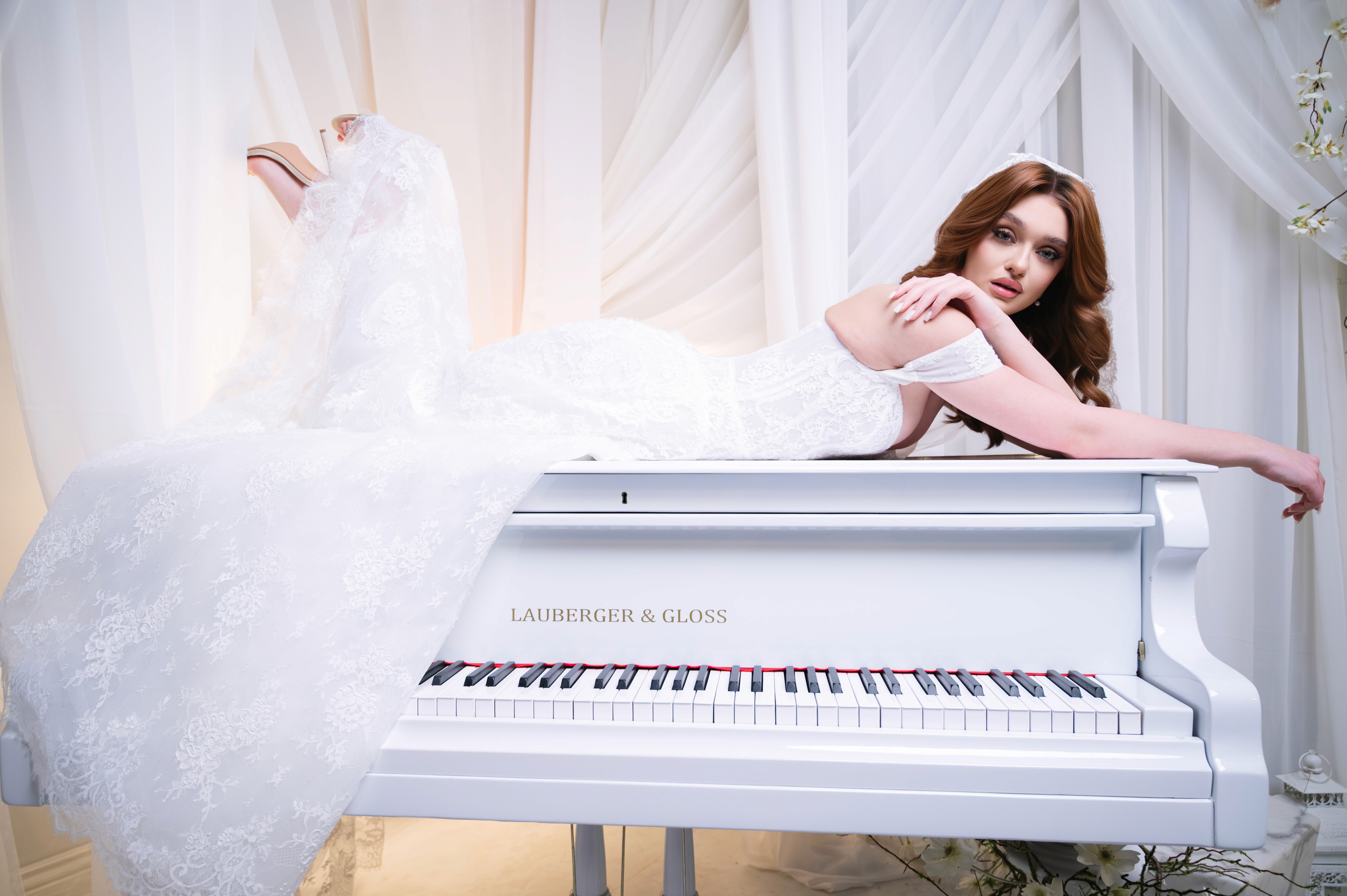 Mireasă fotografiată pe pian într-un decor romantic cu voaluri și lumină soft, fotografie de nuntă în București