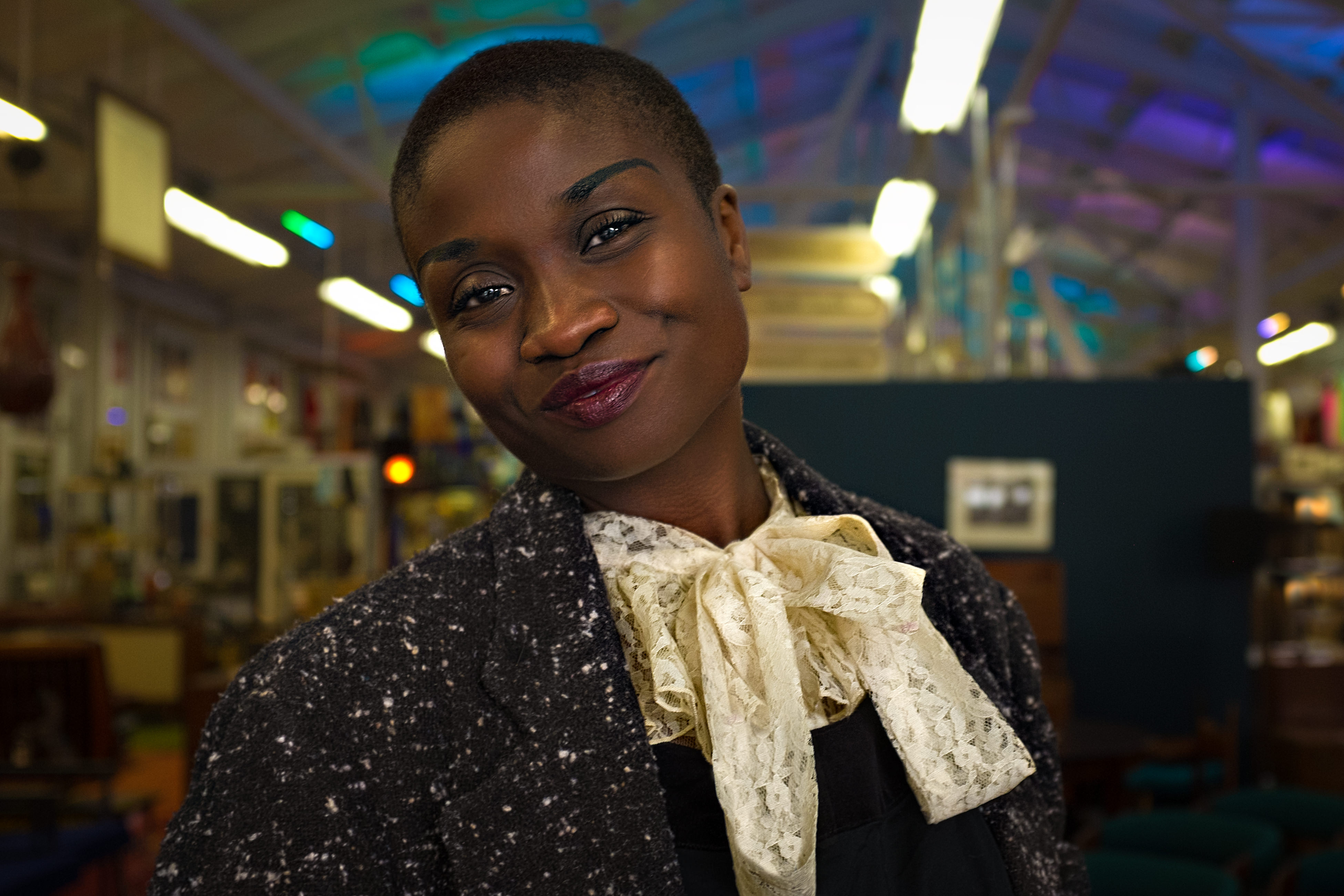 Stylized portrait of Black woman in sequined blazer with white bow tie in creative workspace
