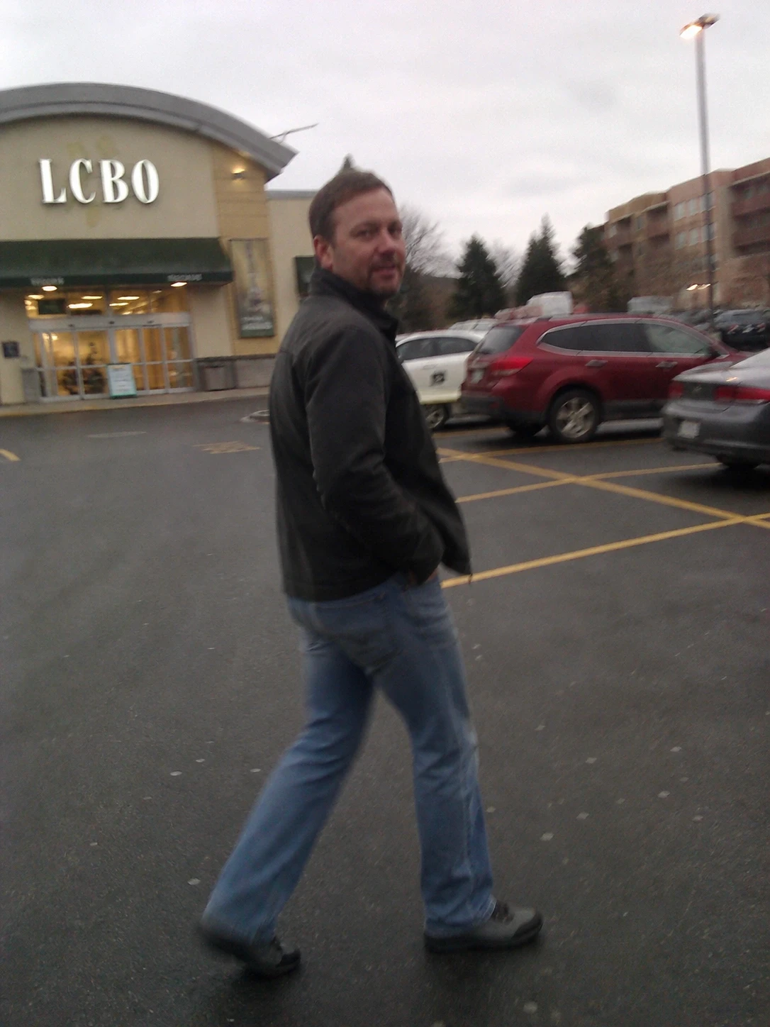 Man walking through parking lot near storefront