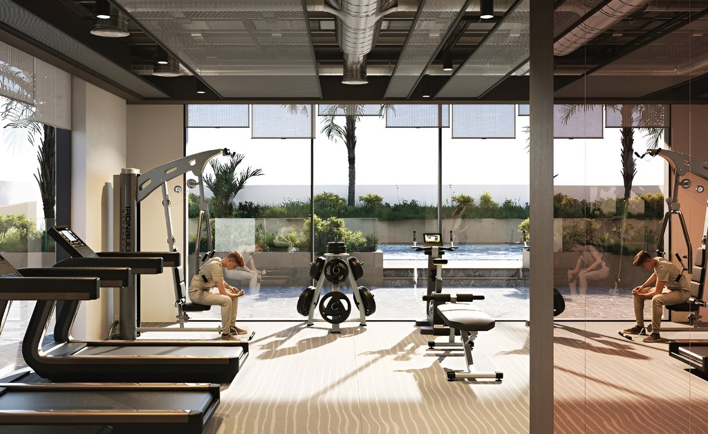 A gym room in Aizel Tower featuring a large window and a treadmill, providing a bright and spacious workout environment.