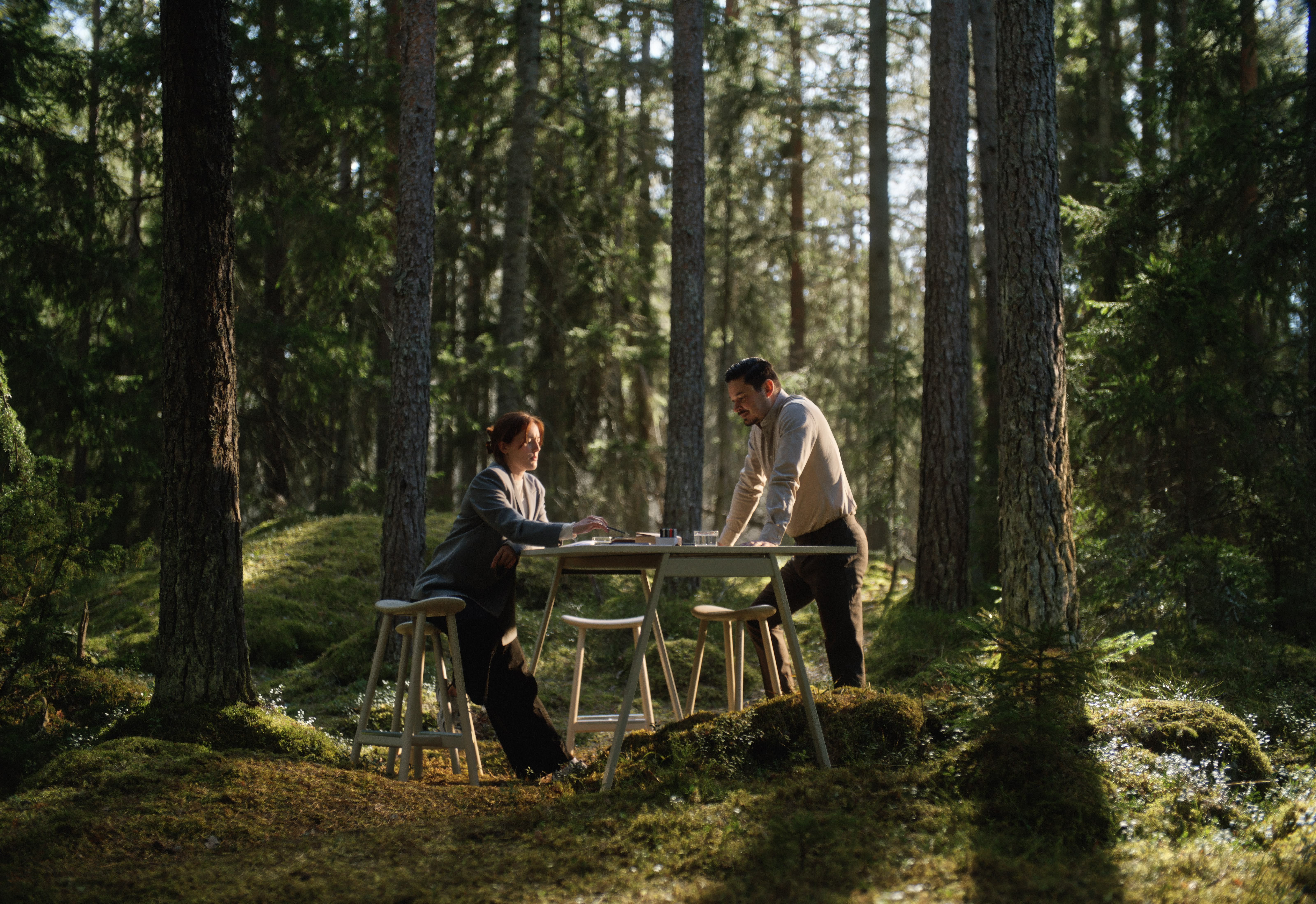 Sunlight streaming through lush green trees, casting shadows on a modern architectural building with glass panels and vertical wooden slats.