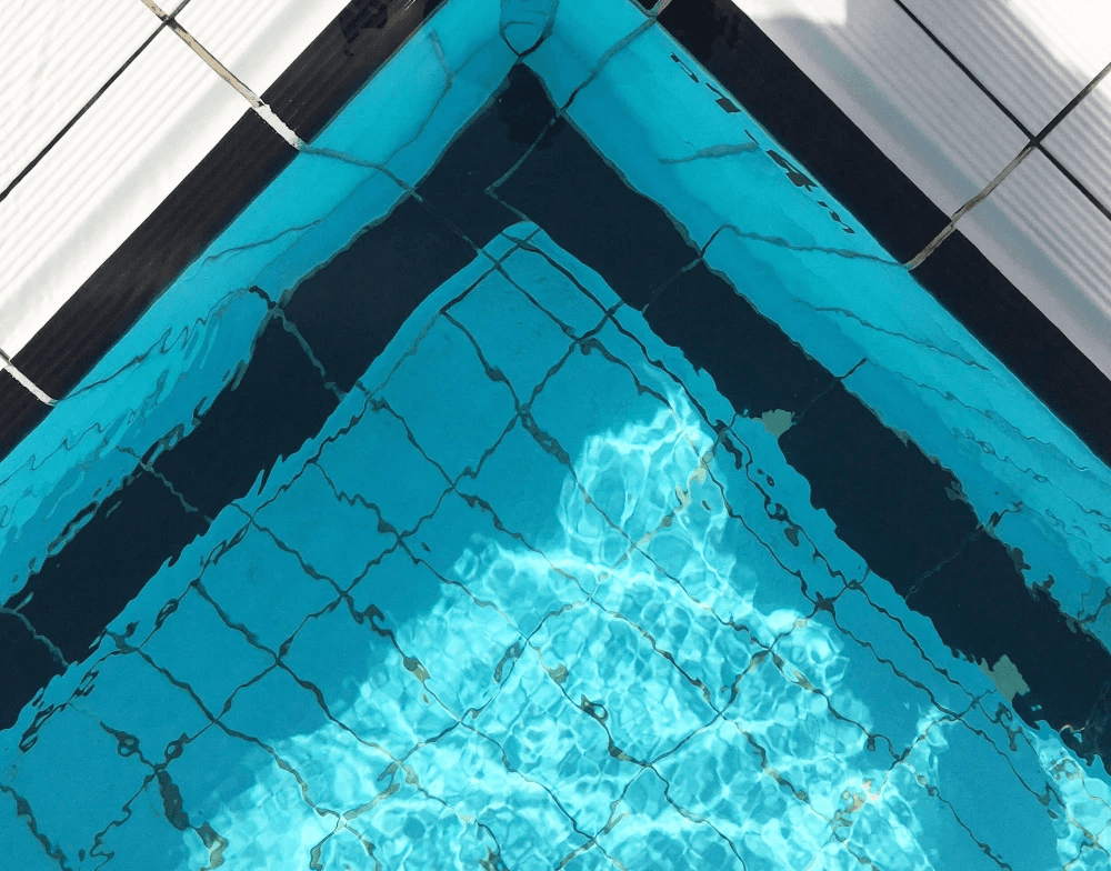 Underwater view of a bright blue freshwater pool with clear tiled patterns.