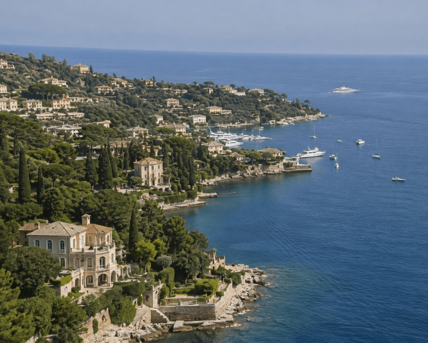 A sweeping aerial view of a steep, lush green hillside lined with luxury Mediterranean-style villas overlooking a vibrant deep blue sea. The grand multi-story stone estate in the lower left features elegant arched loggias and manicured terraced gardens dropping down to a rocky shoreline. Out in the calm water, multiple white yachts, luxury speedboats, and sailboats are anchored near the coastline under a clear blue sky.