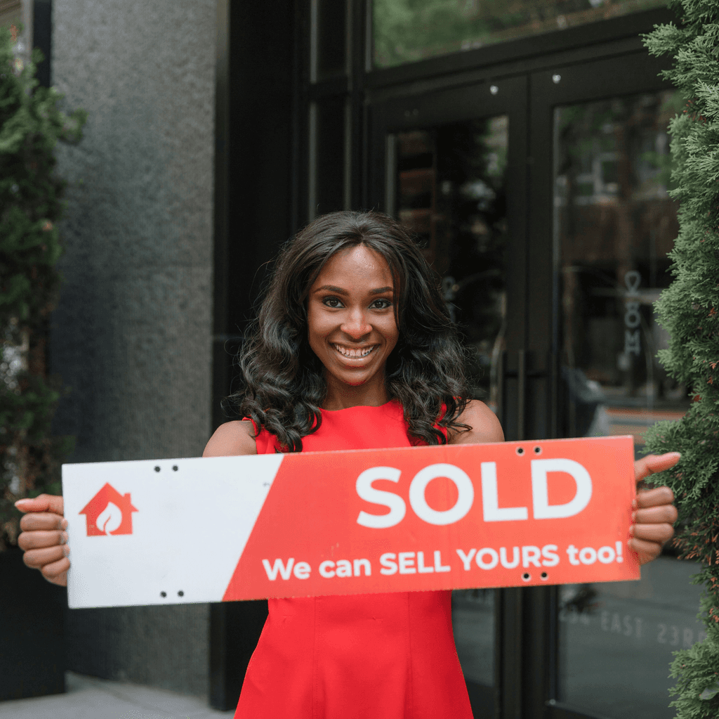 A woman holding a property sold sign