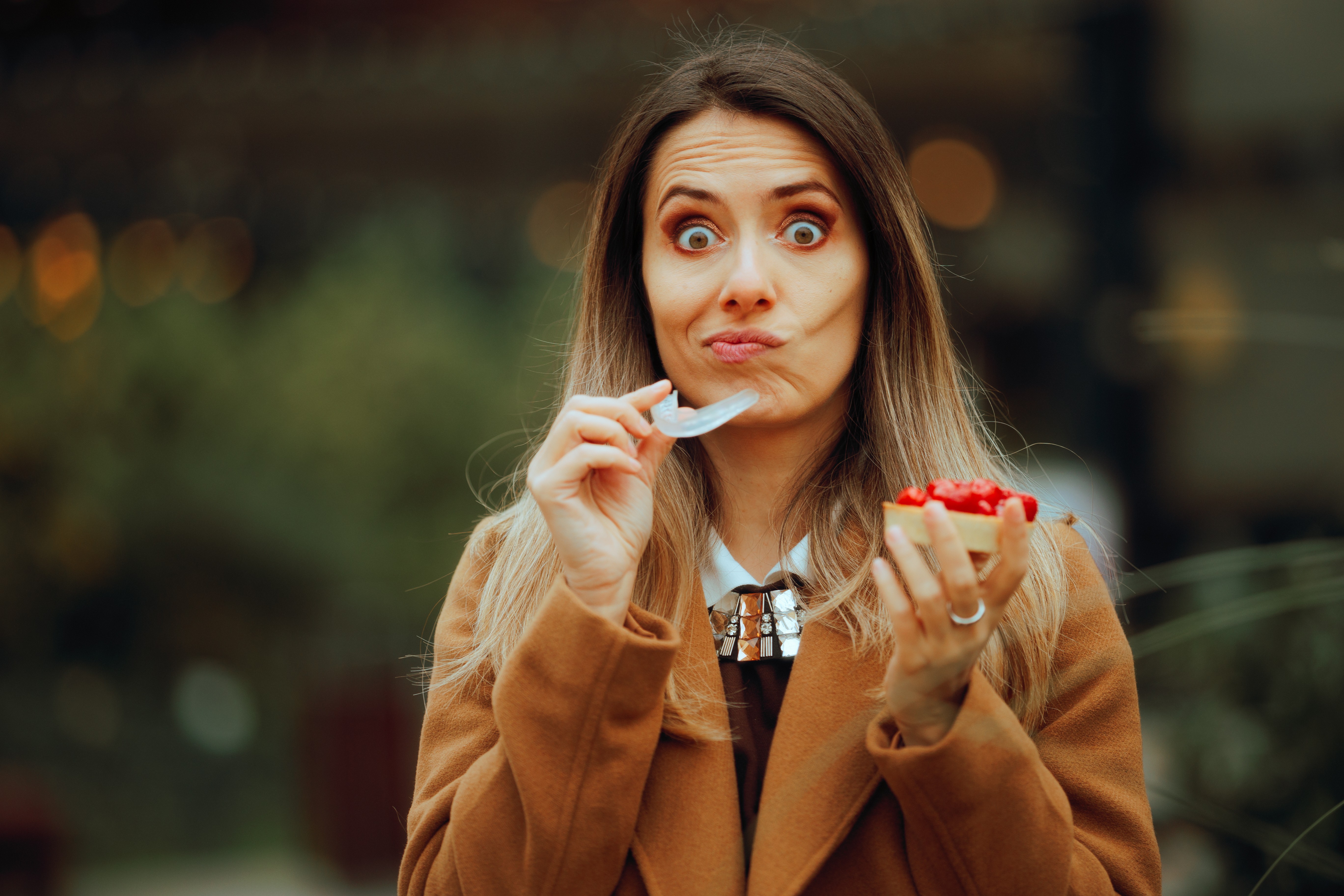 Woman taking out retainer to eat street food 