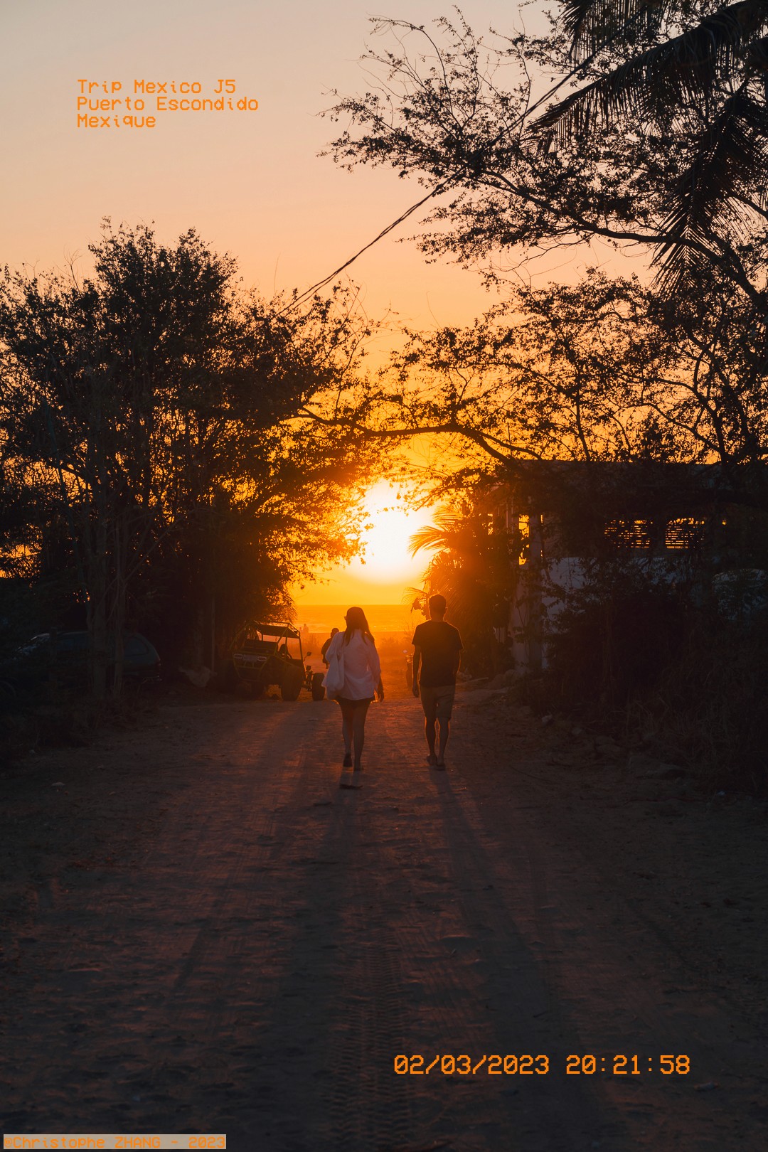 Couple marchant vers le soleil couchant, sentier sableux  