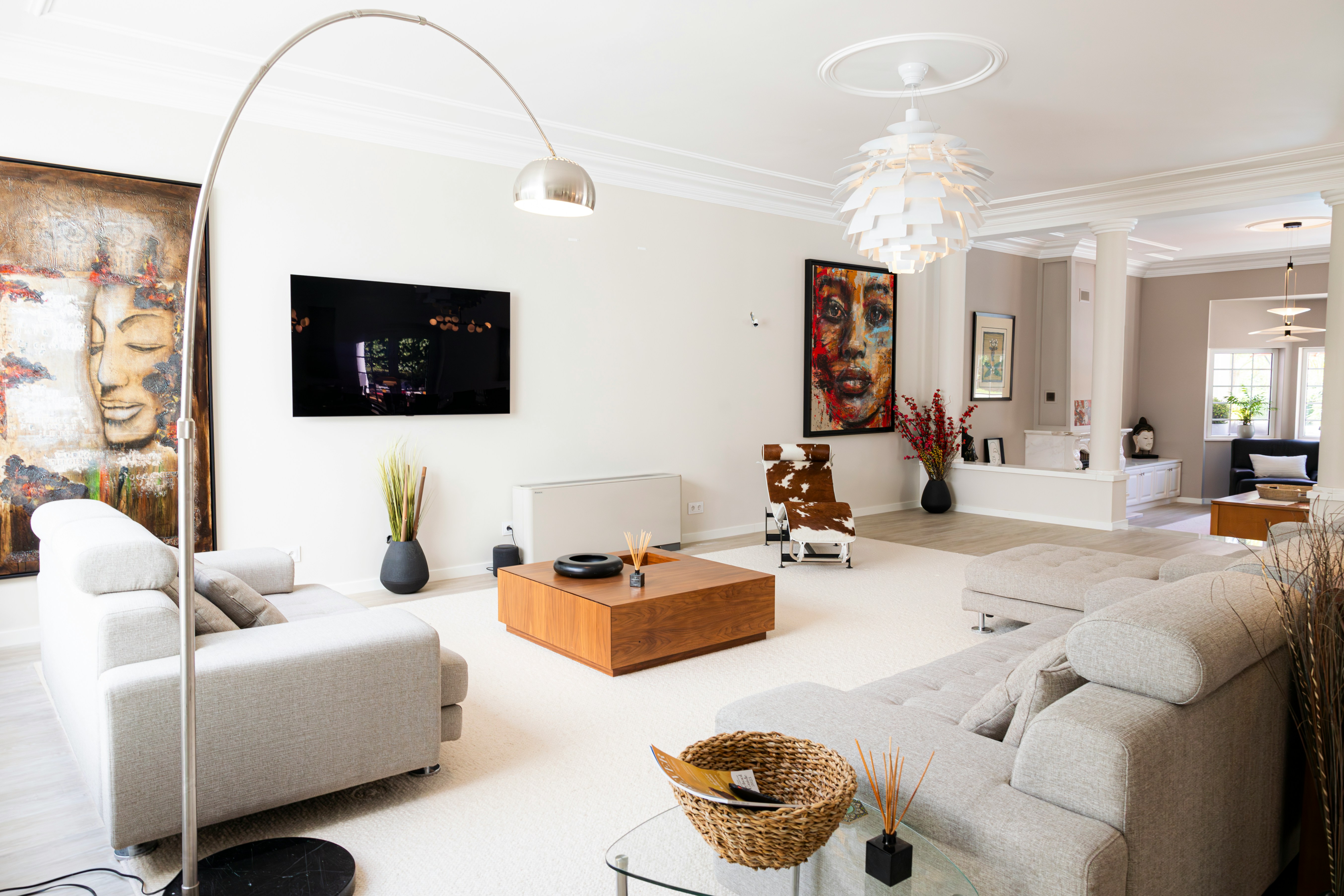 Eclectic contemporary living room with bold artwork, arc lamp, and neutral linen sofas