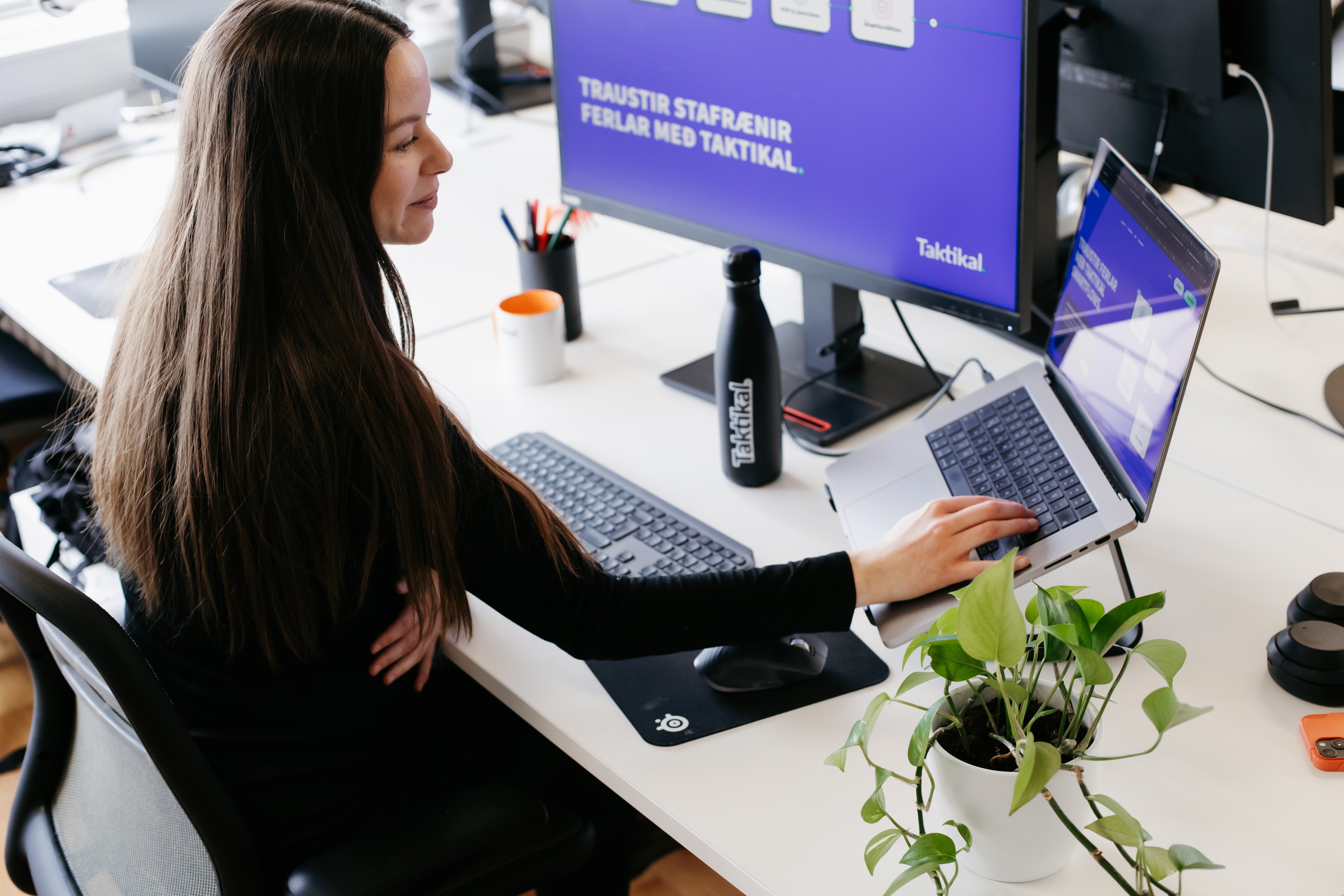 A person sitting at a desk with messaging about Taktikal displayed on screens on the desk