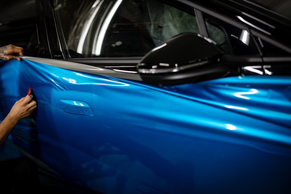 etaljbild på hantverkare som folierar bakre delen av en blå bil, fordonsprofilering.
