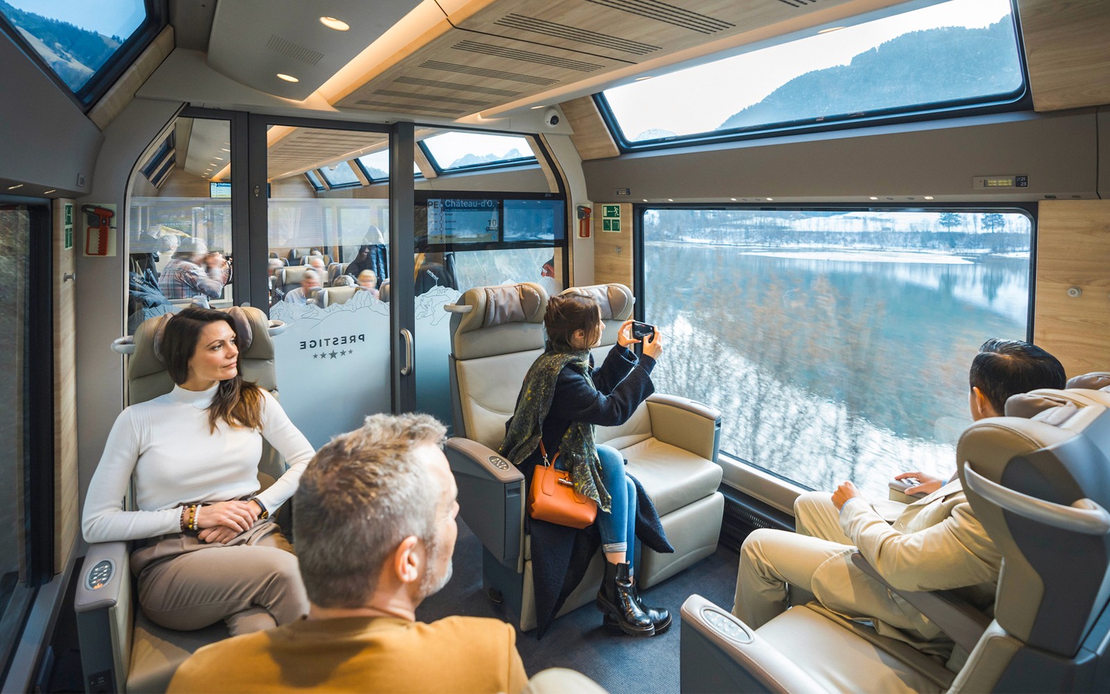 Passengers enjoying views on the GoldenPass Express train from Montreux to Interlaken.