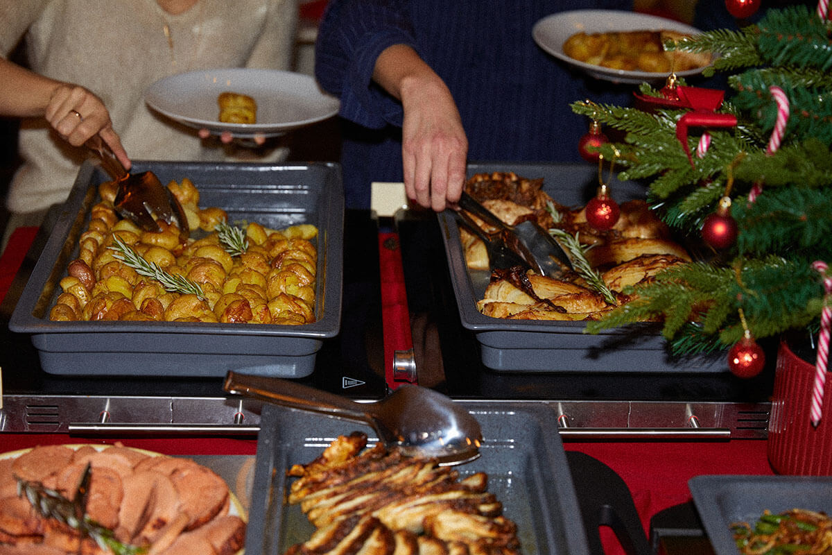 People serving food onto their plate from a buffet