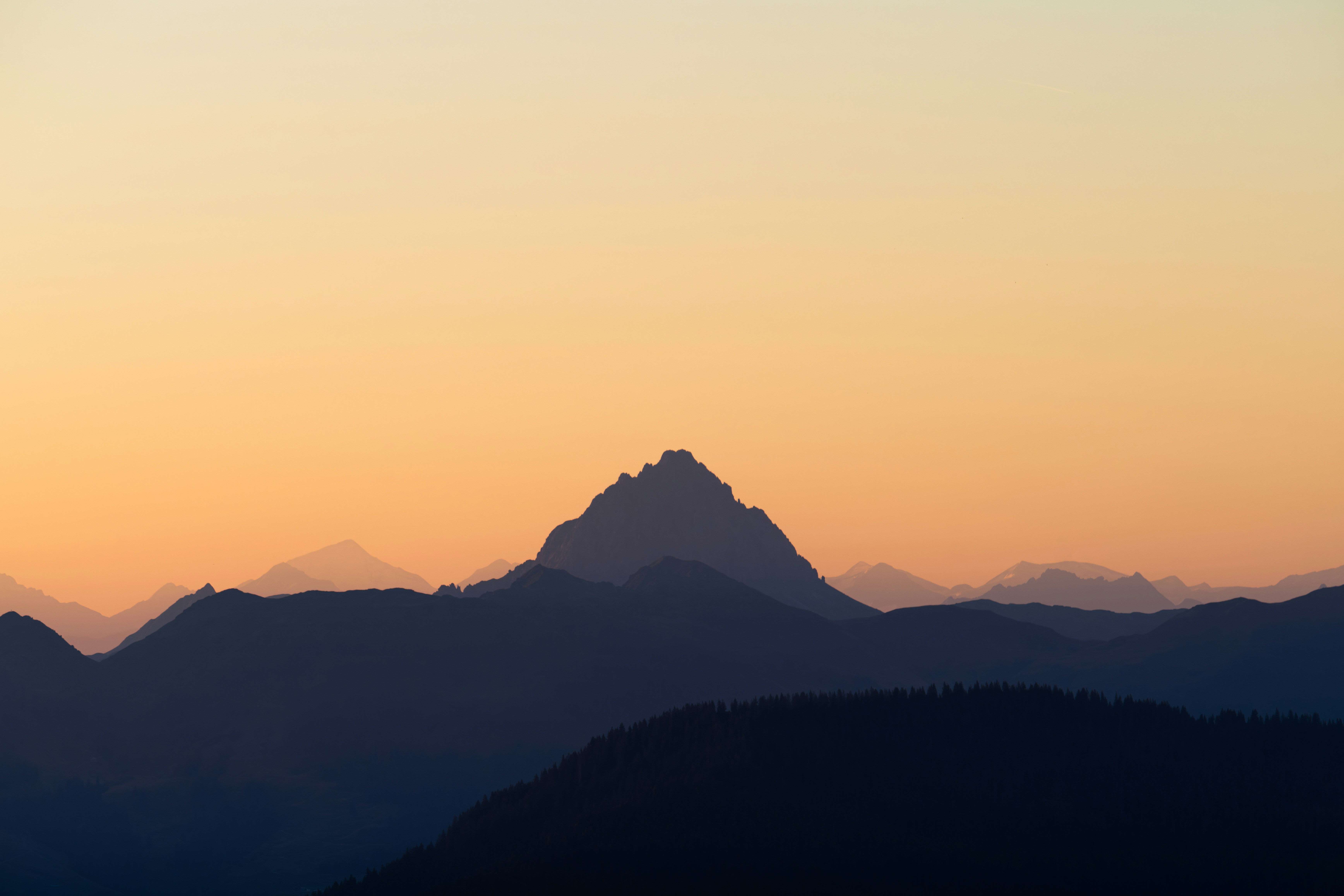 Silhouetted mountain peaks against a warm sunset sky
