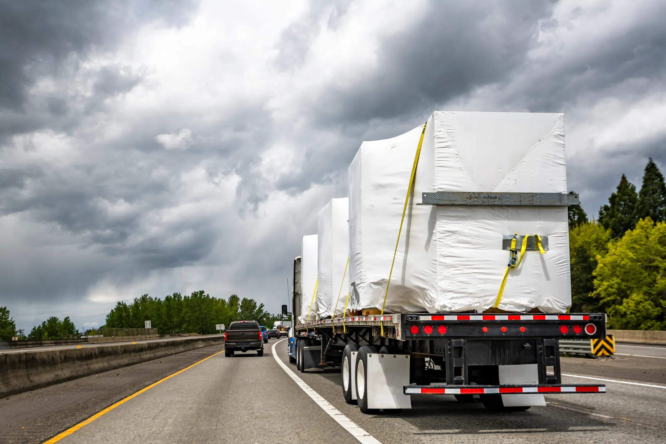 Flatbed truck transporting secured cargo on a highway, illustrating motor truck cargo insurance coverage