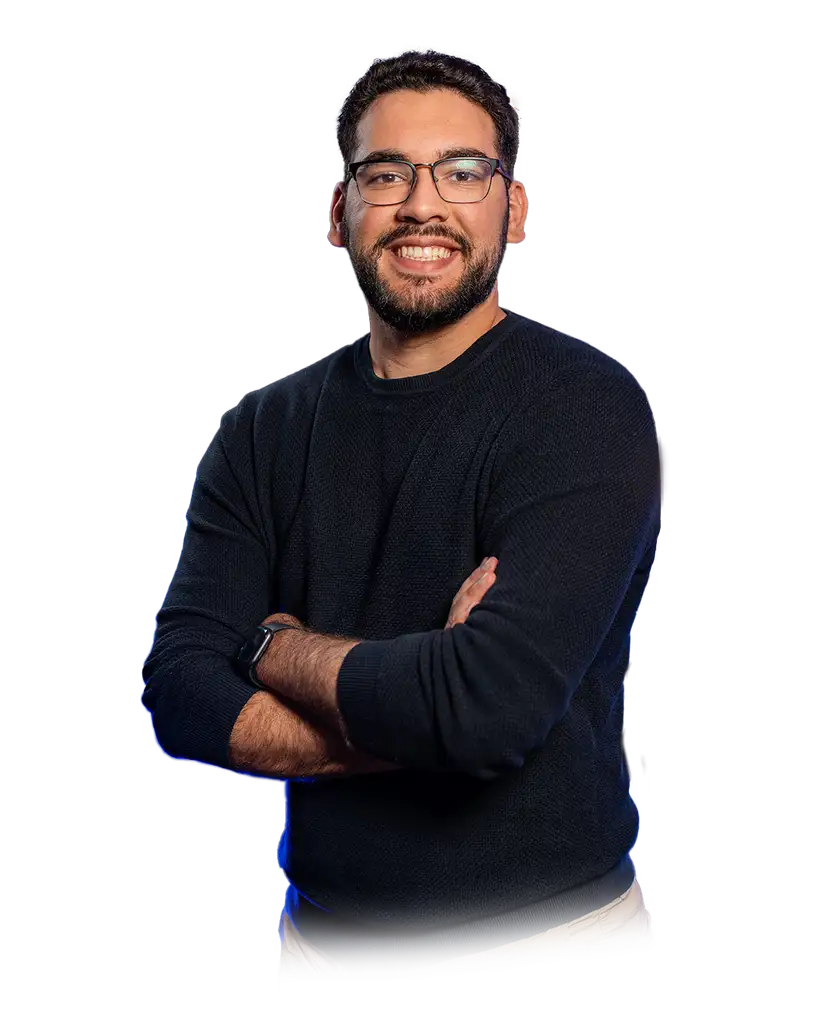 Man with glasses smiling, arms crossed, wearing a black long-sleeve shirt.