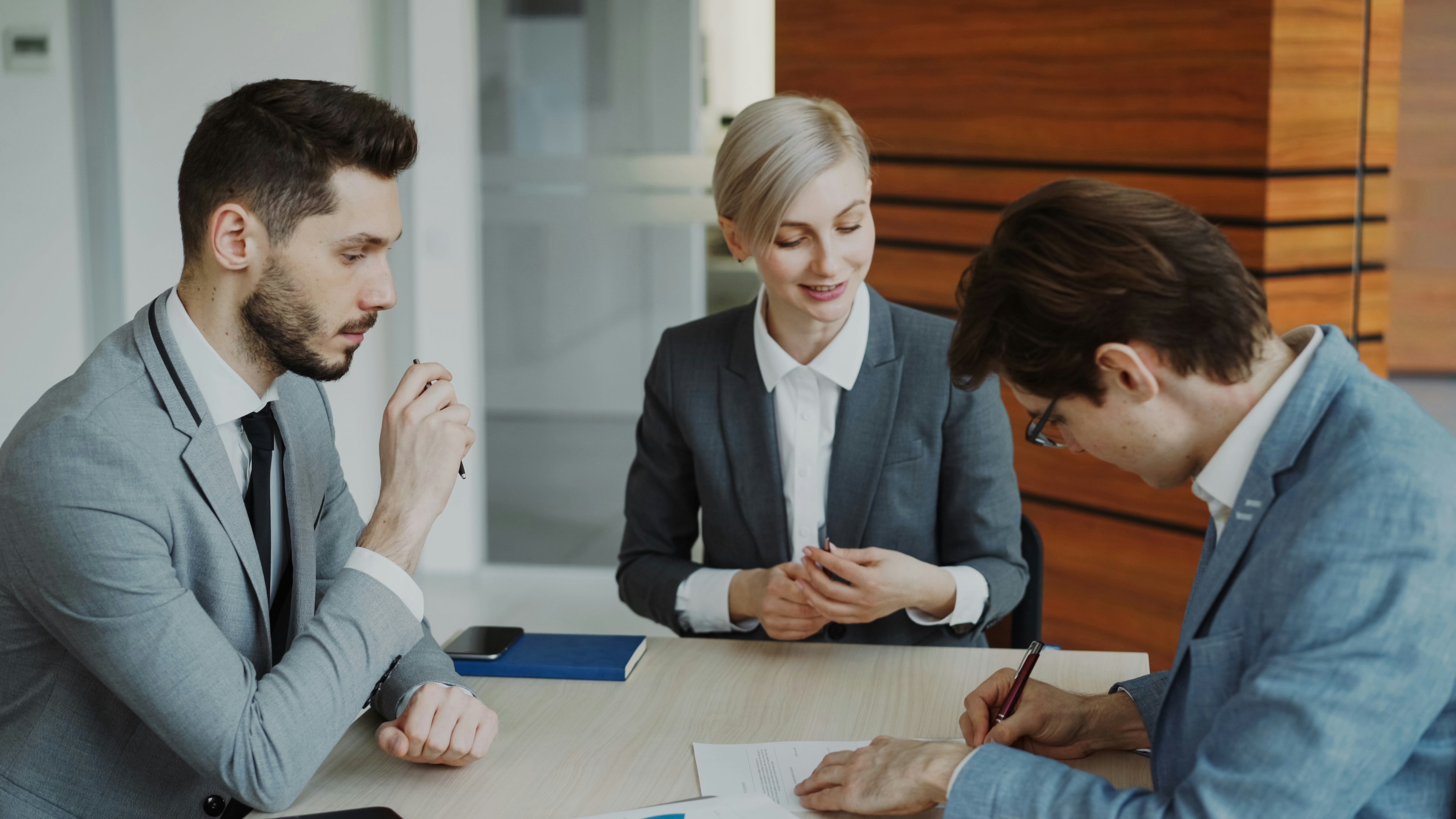 Business people signing a contract at a table.