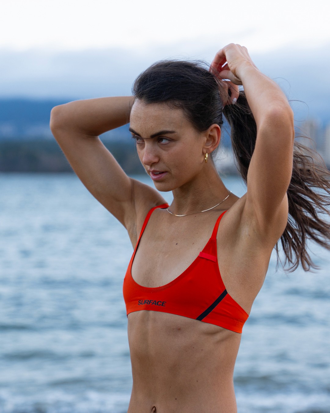 Athlete standing on riverside rocks wearing Surface Athletics performance swimwear designed for freedom of movement and high-performance in and out of the water.