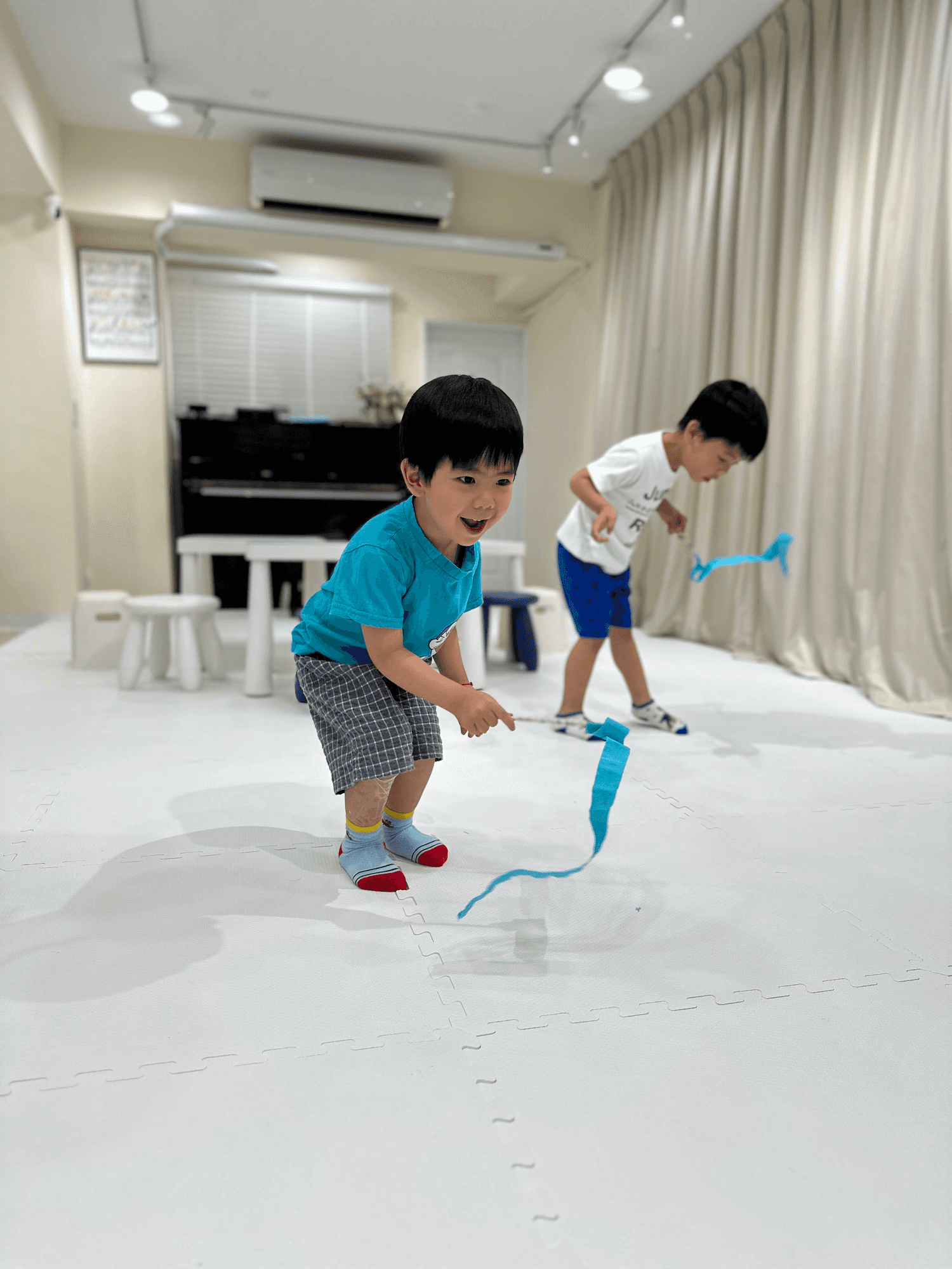 Studio portrait of a young person with blond hair, wrapped in translucent orange fabric against a blue background