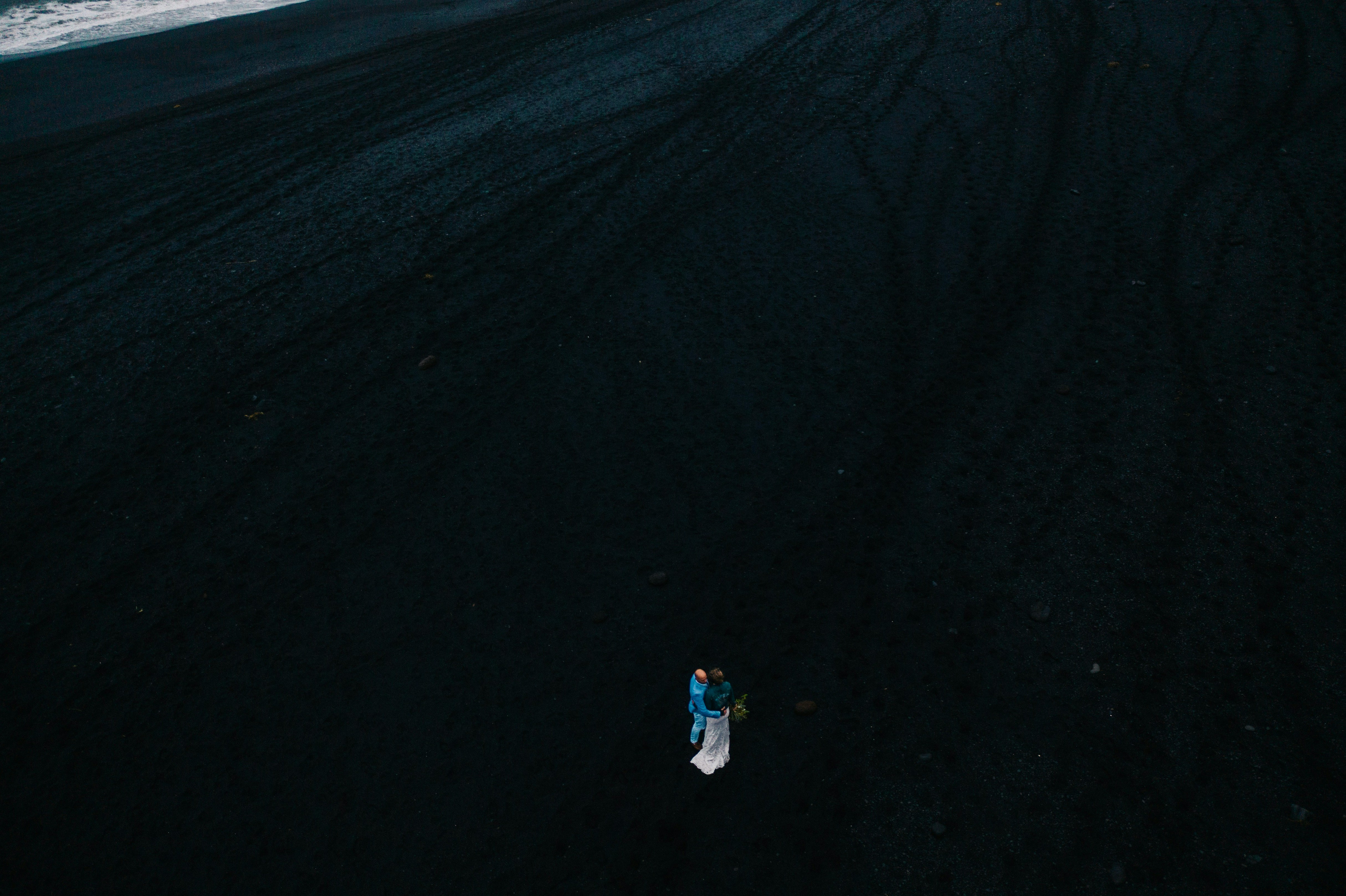 Wedding couple walking along a black sand beach in Iceland.