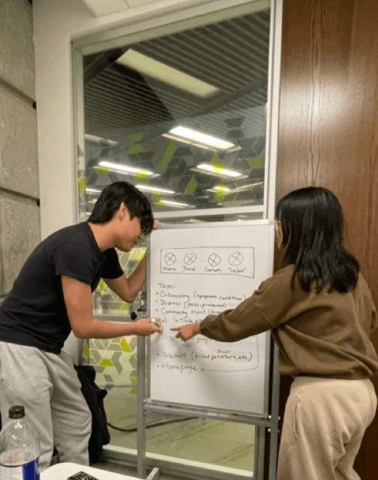 Man and a woman pointing to sketches on a whiteboard