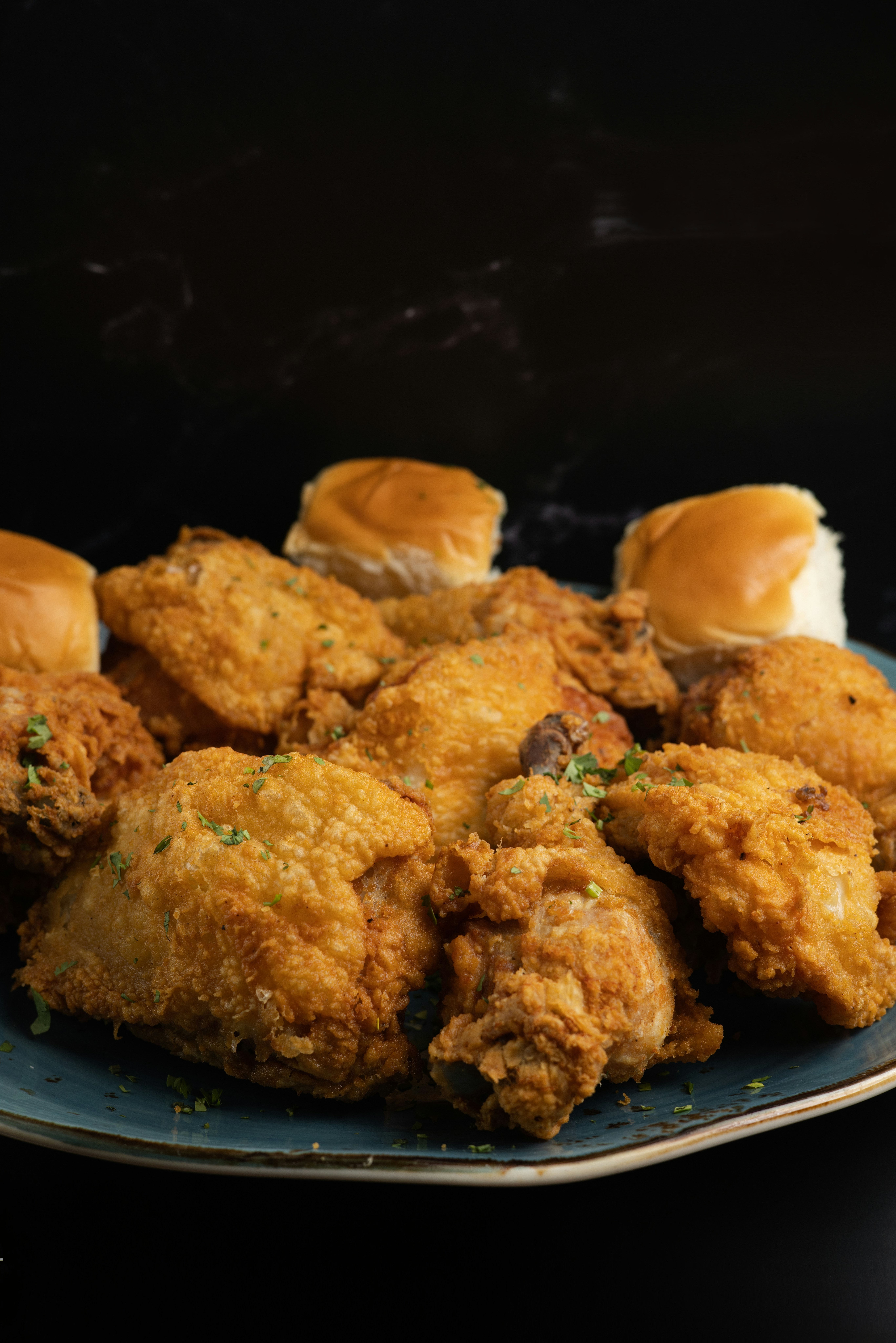 Crispy fried chicken and dinner rolls on a plate