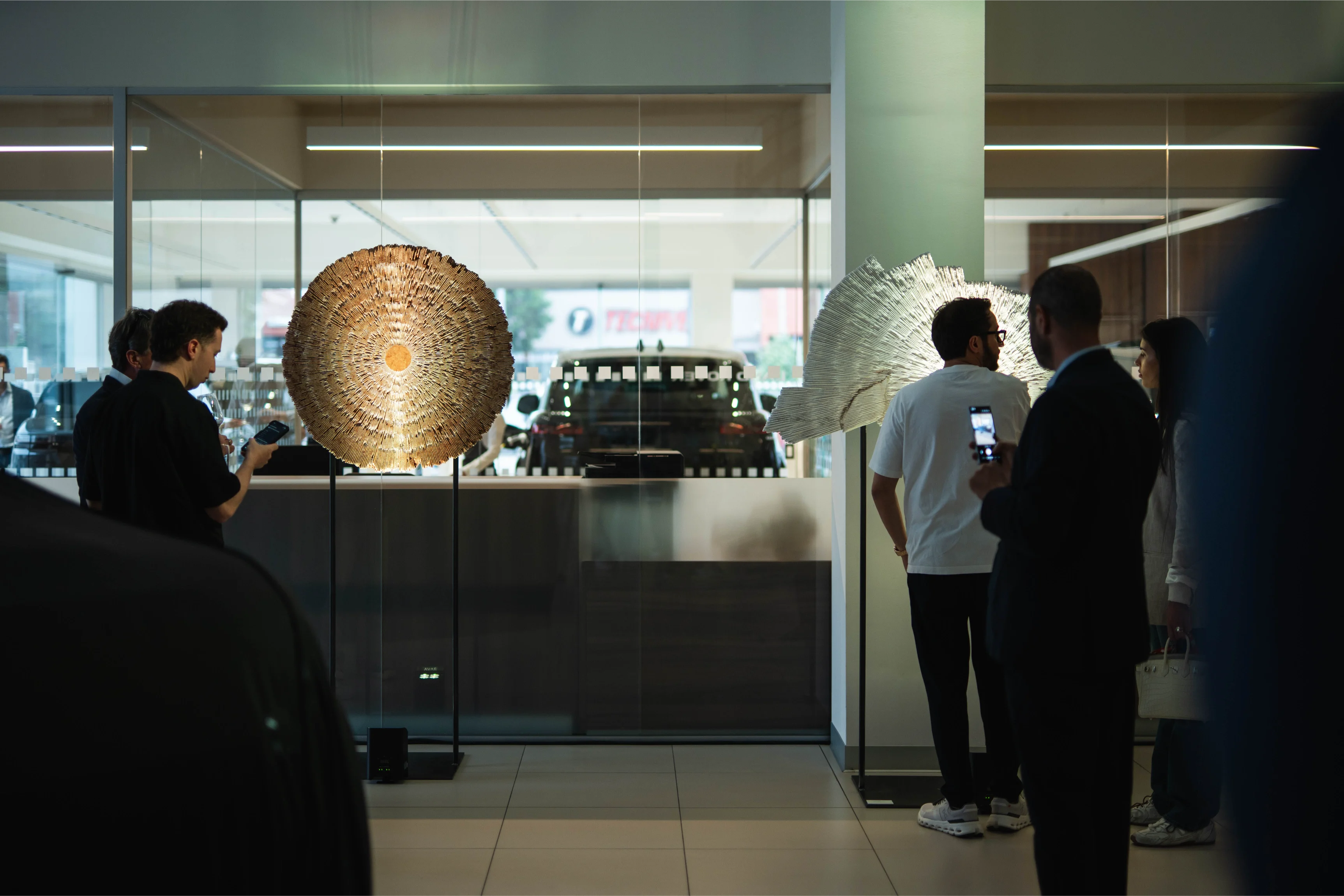 Opera di arte OCTA - Land Rover realizzata da iStone Arte installata in showroom aziendale durante evento inaugurale, sculture radiali illuminate e pubblico in interazione con le opere