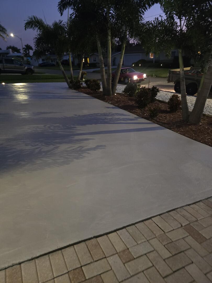 A smiling woman with her arms crossed, standing against a dark green background. She has long, dark hair.