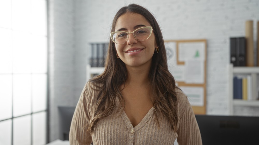 Jeune femme souriante dans un bureau, symbolisant la simplicité de comprendre les avantages de l'assurance vie permanente.