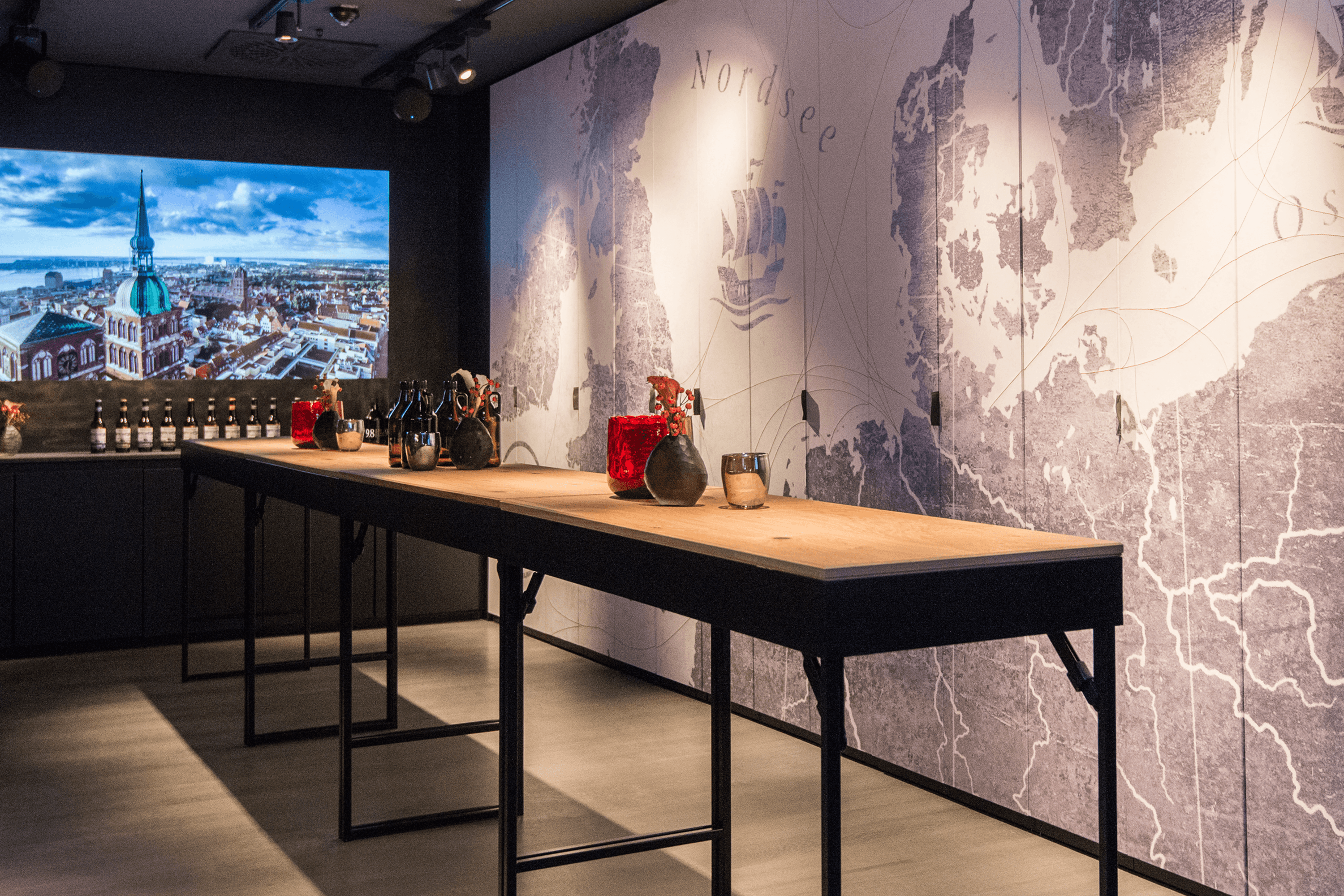 Bottles and vases on a wooden display table with a map mural.