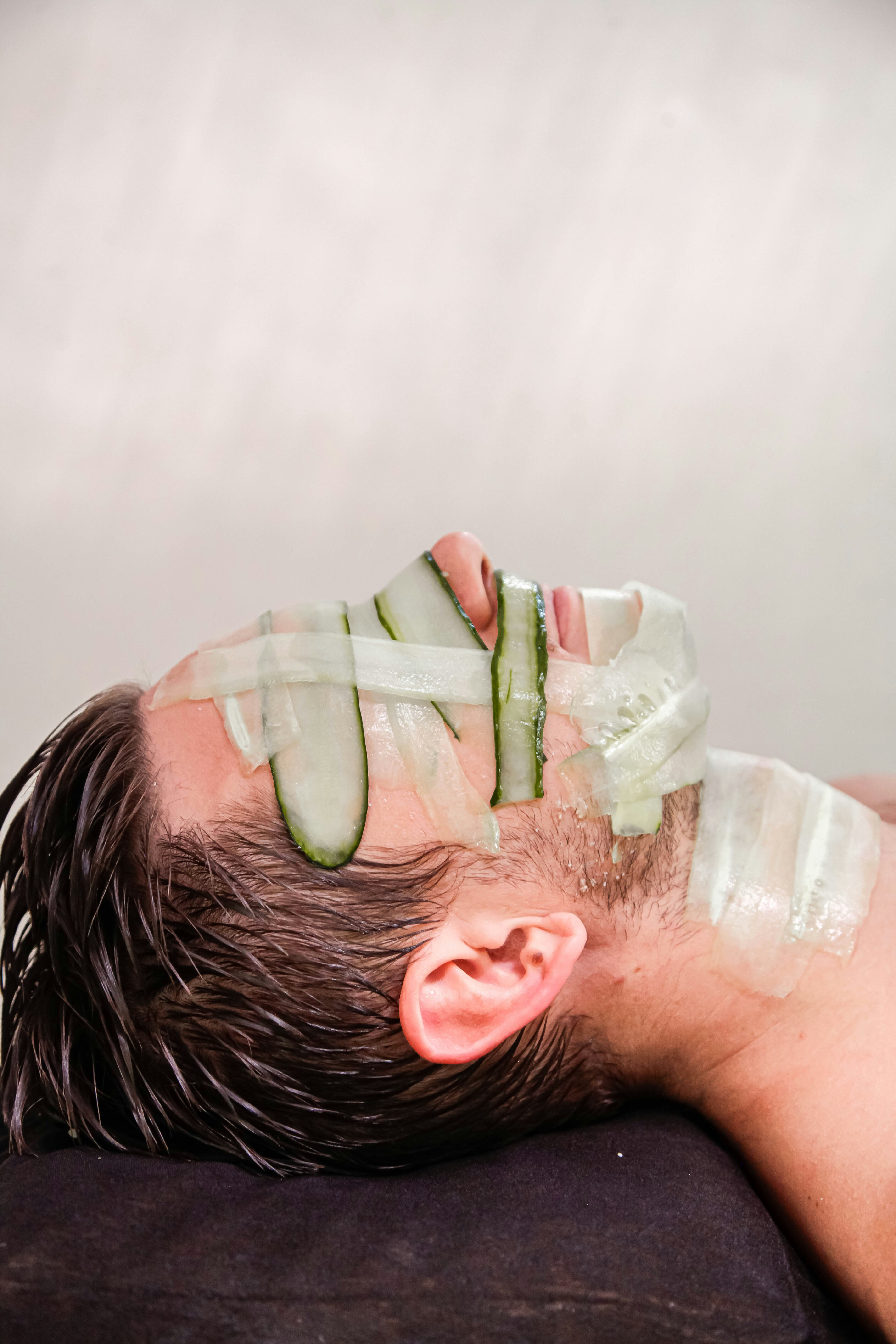 A man with cucumber on his face laying on a pillow