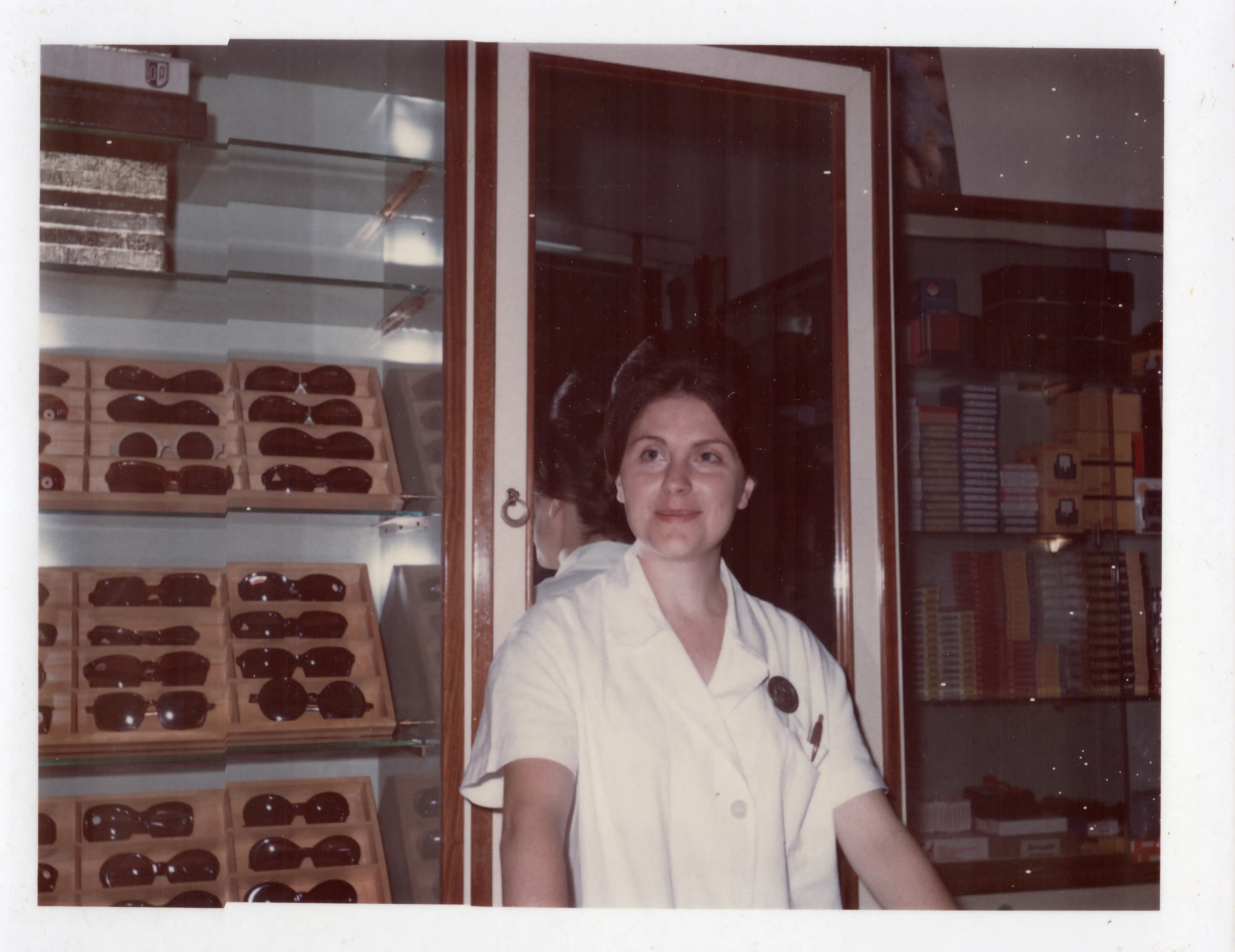 Fotografia d’archivio del negozio storico che racconta il passaggio generazionale nella storia di Ottica Dentella ad Ancona, con una delle protagoniste della famiglia ritratta davanti all’esposizione di occhiali e montature. L’immagine rappresenta la continuità di un’attività ottica nata nel 1956 e portata avanti attraverso più generazioni, mantenendo al centro competenza, qualità, ricerca nella visione e cura personale del cliente.