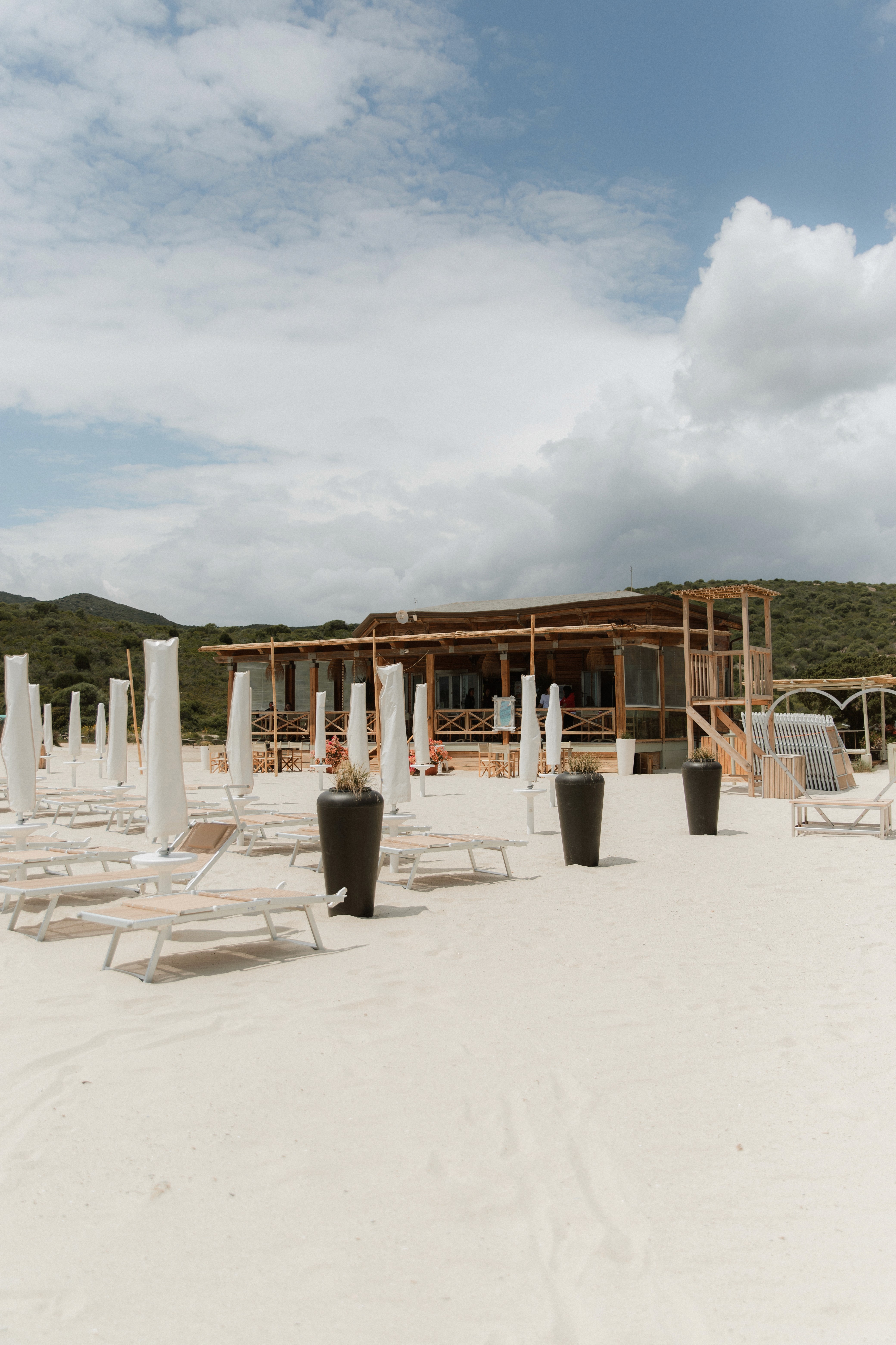 A beach with lounge chairs and umbrellas on the sand