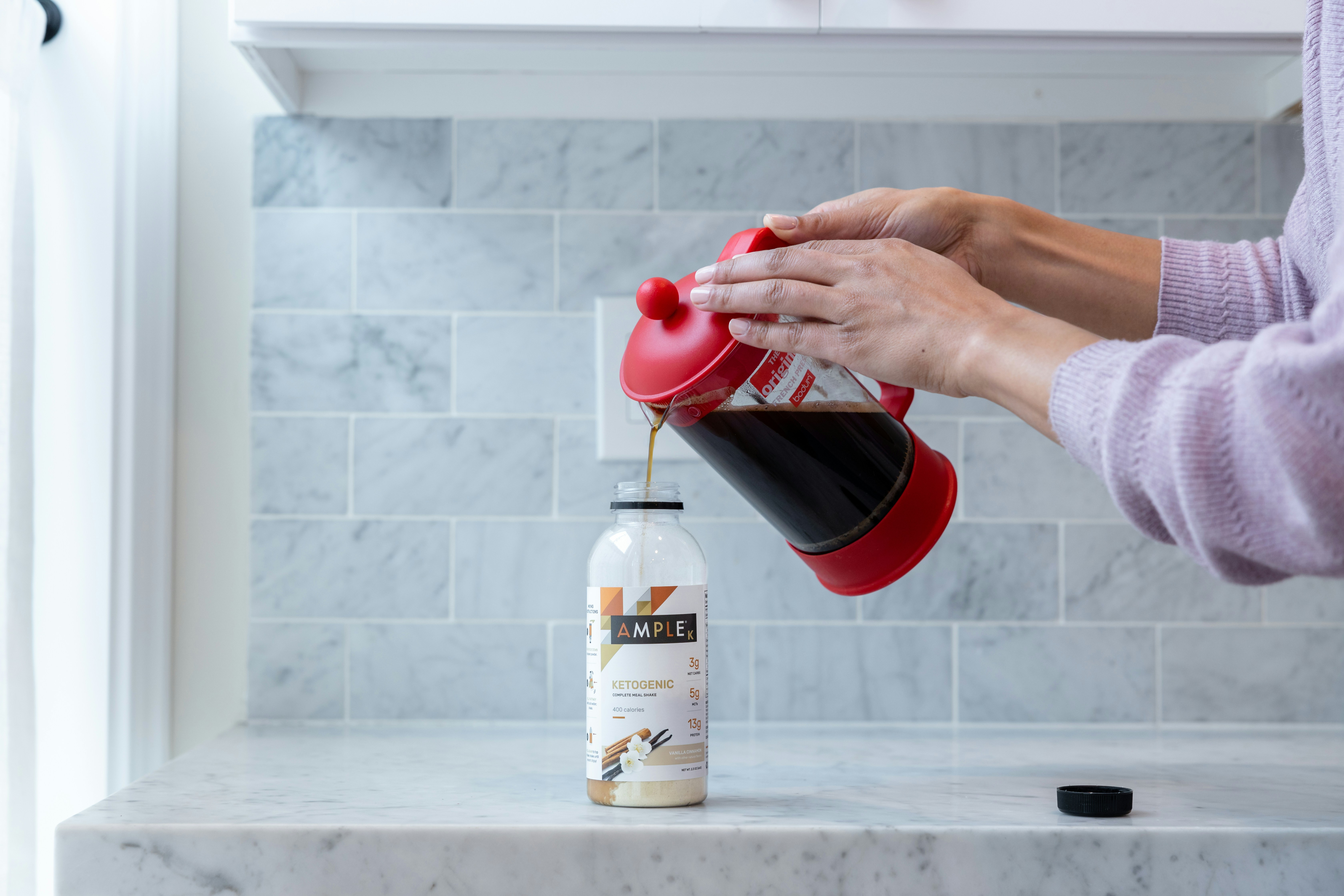person pouring red liquid on white plastic bottle