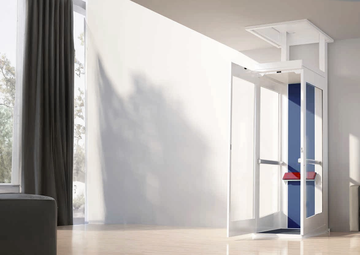 Elevate AVA Swift through-floor home lift in a residential interior — white aluminium frame with full-height glass panels, blue upholstered interior and red fold-down seat, open hinged door showing compact cabin at lower landing position