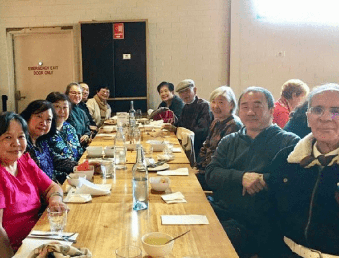A restaurant interior featuring marble countertops, brown leather chairs, wood-paneled walls, and round pendant lights hanging above a bar set with wine glasses.