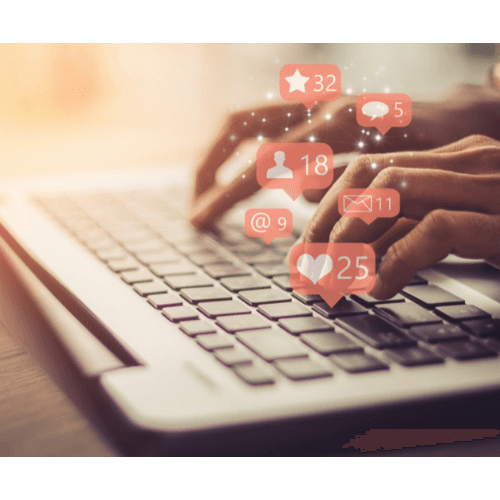 Hands typing on a laptop keyboard with social media notification icons.