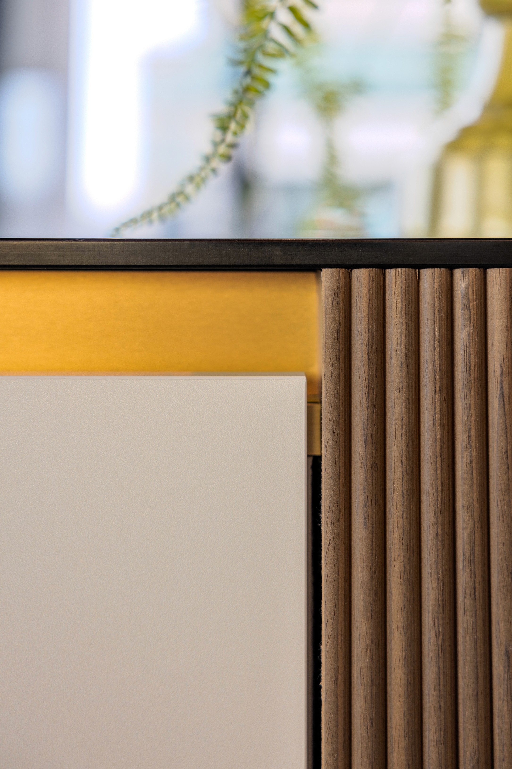 Close-up van materiaal- en afwerkingsdetails in AFAS DotNL: ribbelvormig houten paneel, crèmekleurig oppervlak en goudkleurig accent – projectfotografie DSN Workspace Solutions