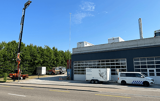 Four diverse professionals collaboratively working on a laptop, with one person pointing at the screen while others observe.