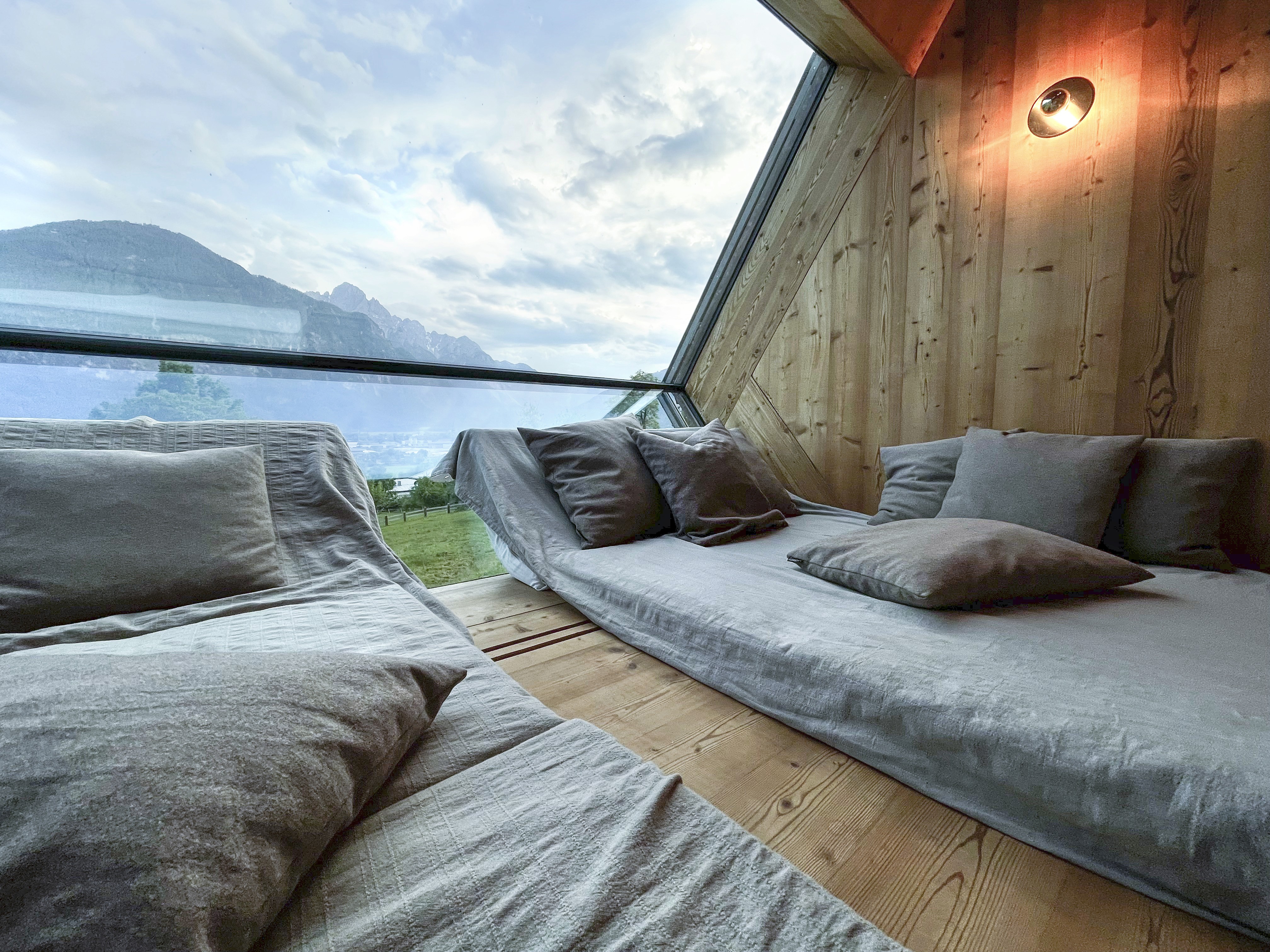 Ufogel’s cosy timber interior with built-in daybeds facing a floor-to-ceiling Alpine view